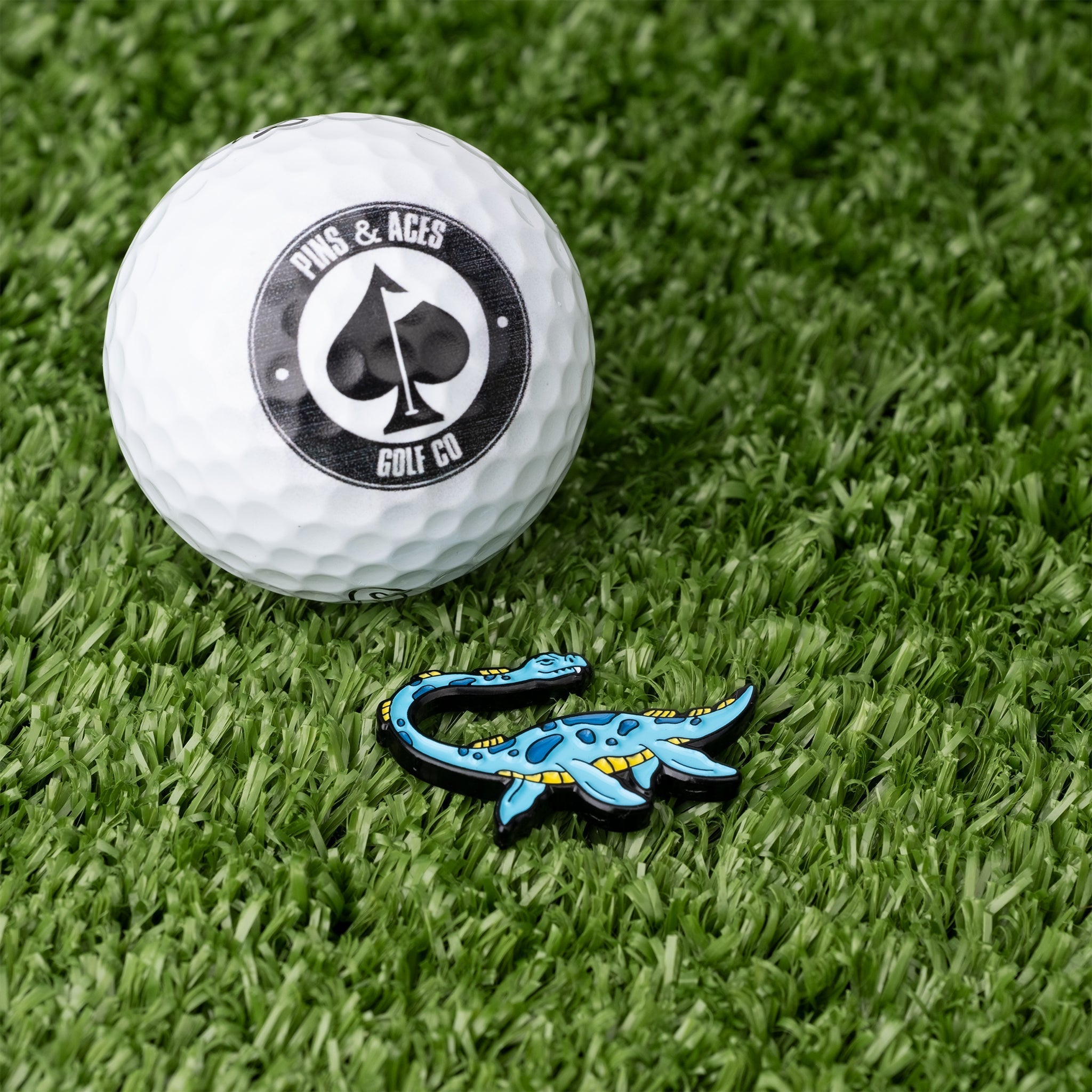 Nessie Ball Marker featuring a colorful Loch Ness monster design next to a golf ball on green turf.