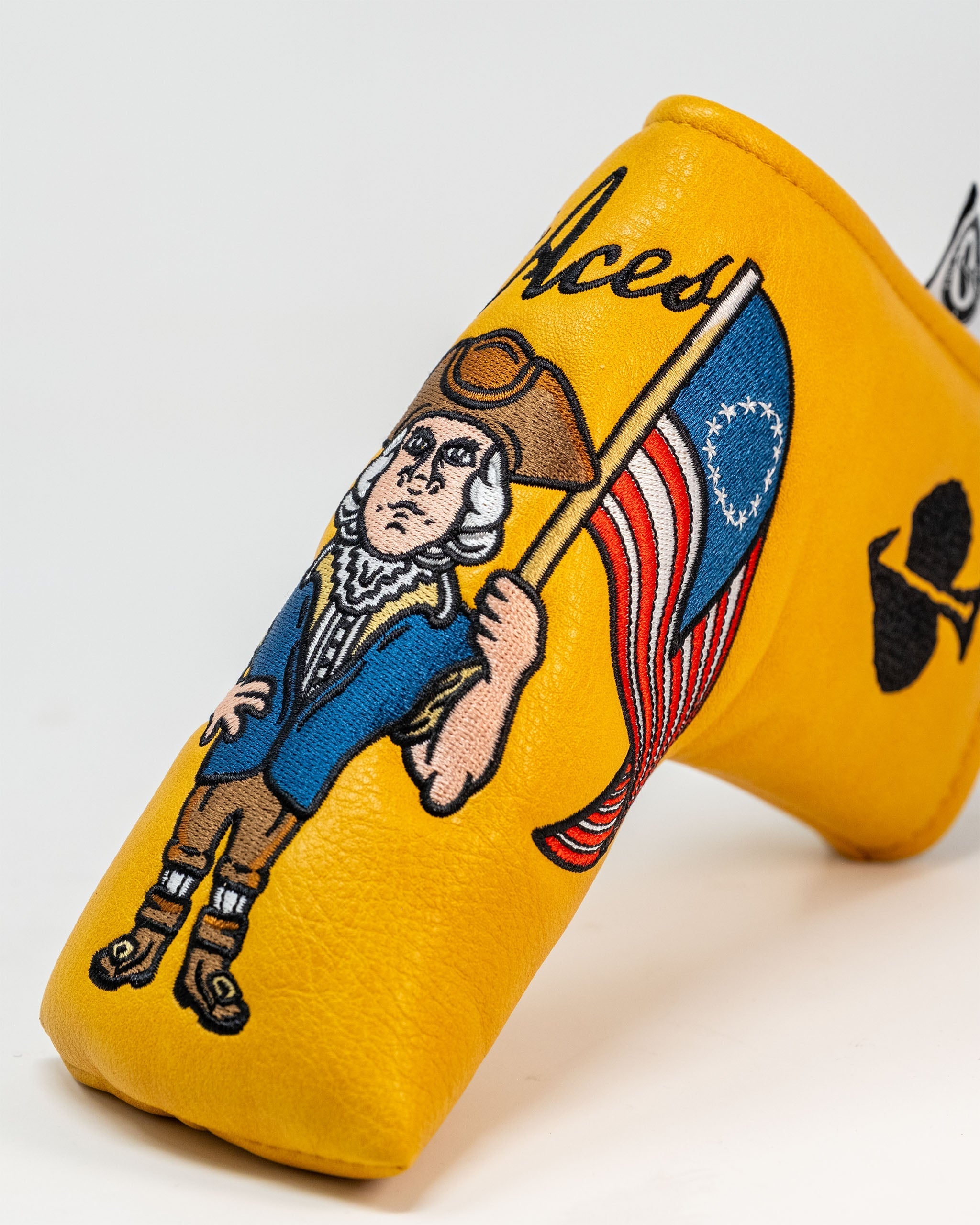Bold yellow putter cover featuring a patriotic design with a historical figure holding an American flag and the Pins and Aces logo.