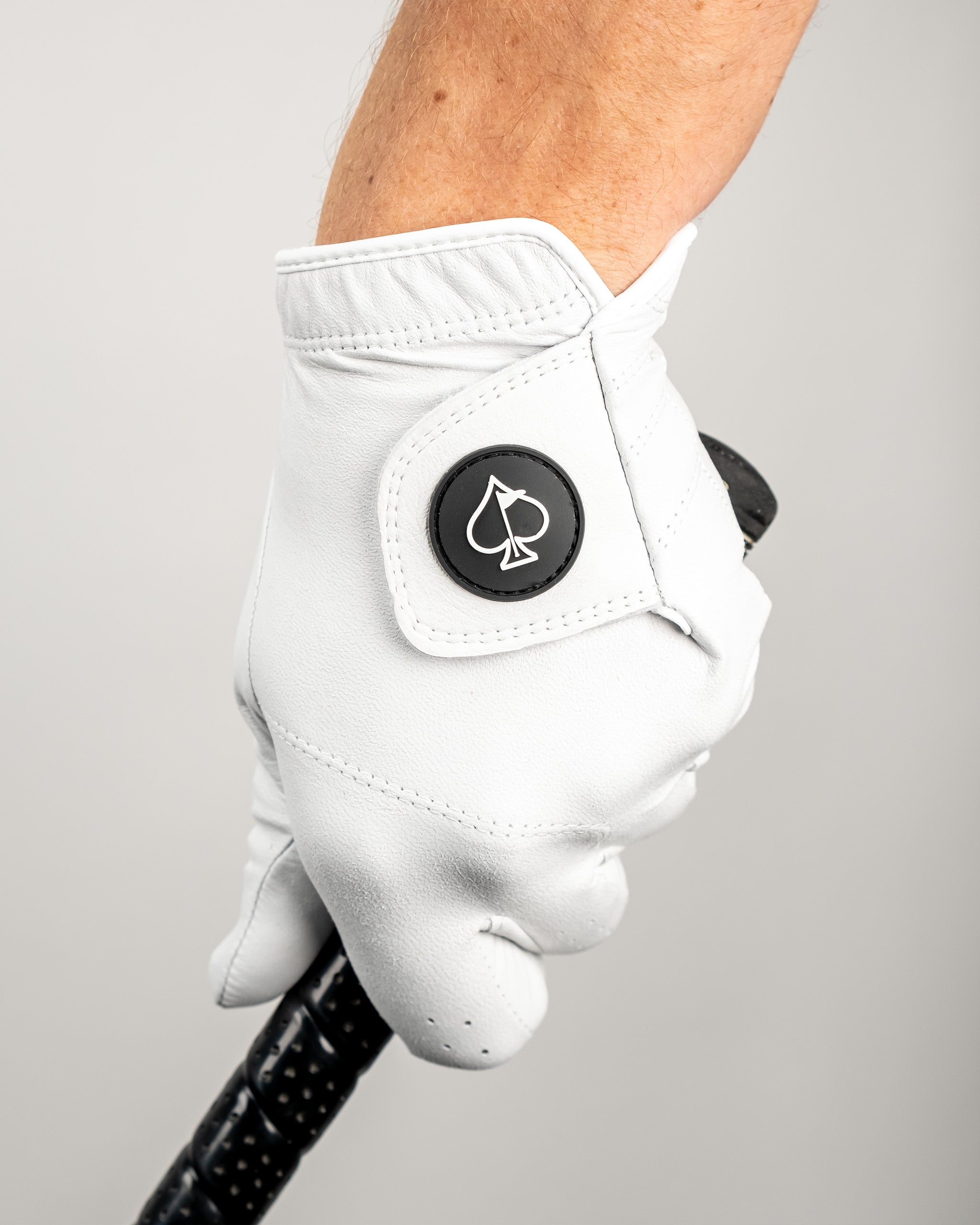 Premium Tour Glove in Ghost White, featuring a sleek design and logo, gripping a golf club for optimal performance.