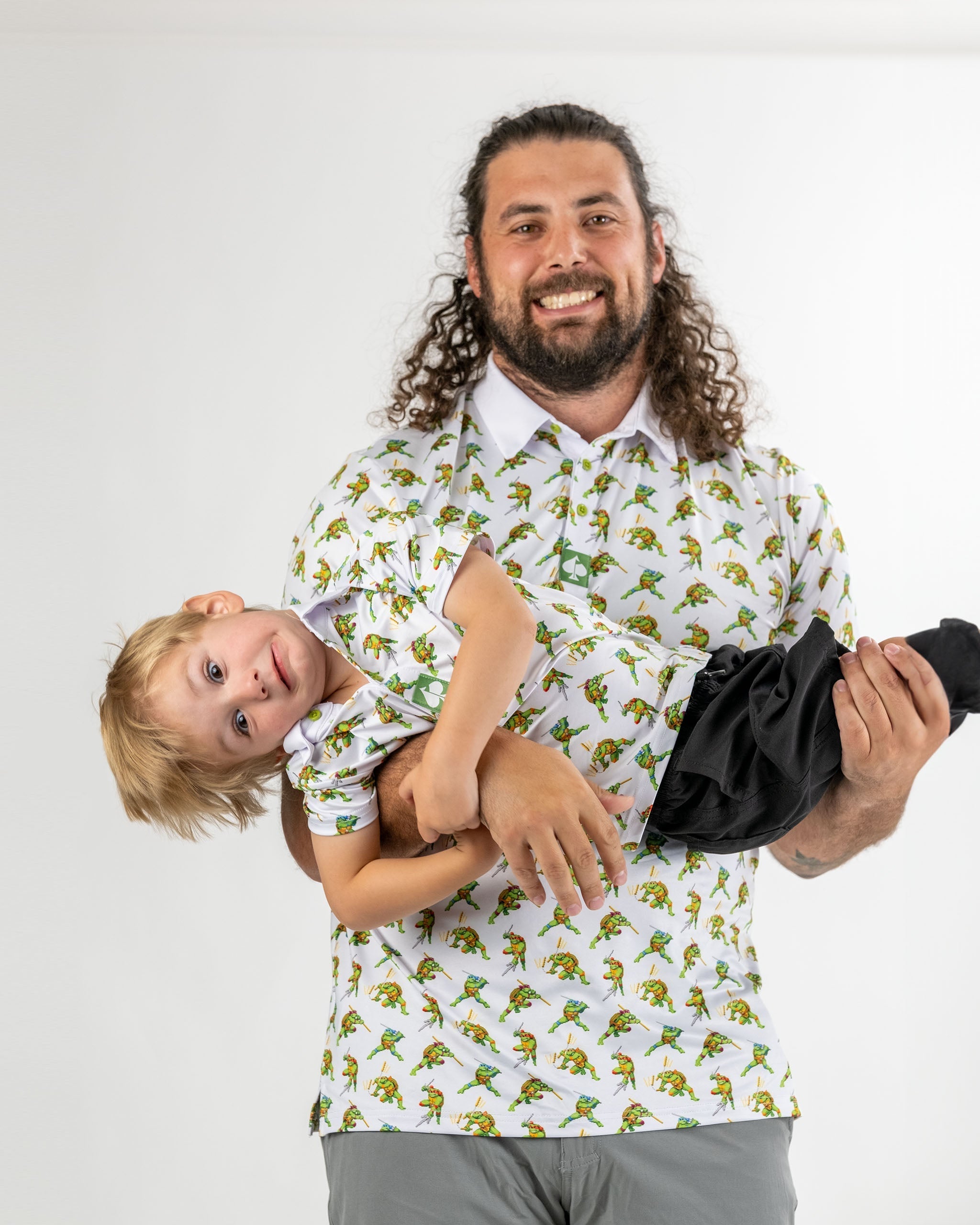 Youth Cowabunga Classic 8-Bit shirt featuring vibrant Teenage Mutant Ninja Turtles design, worn by a man holding a child.