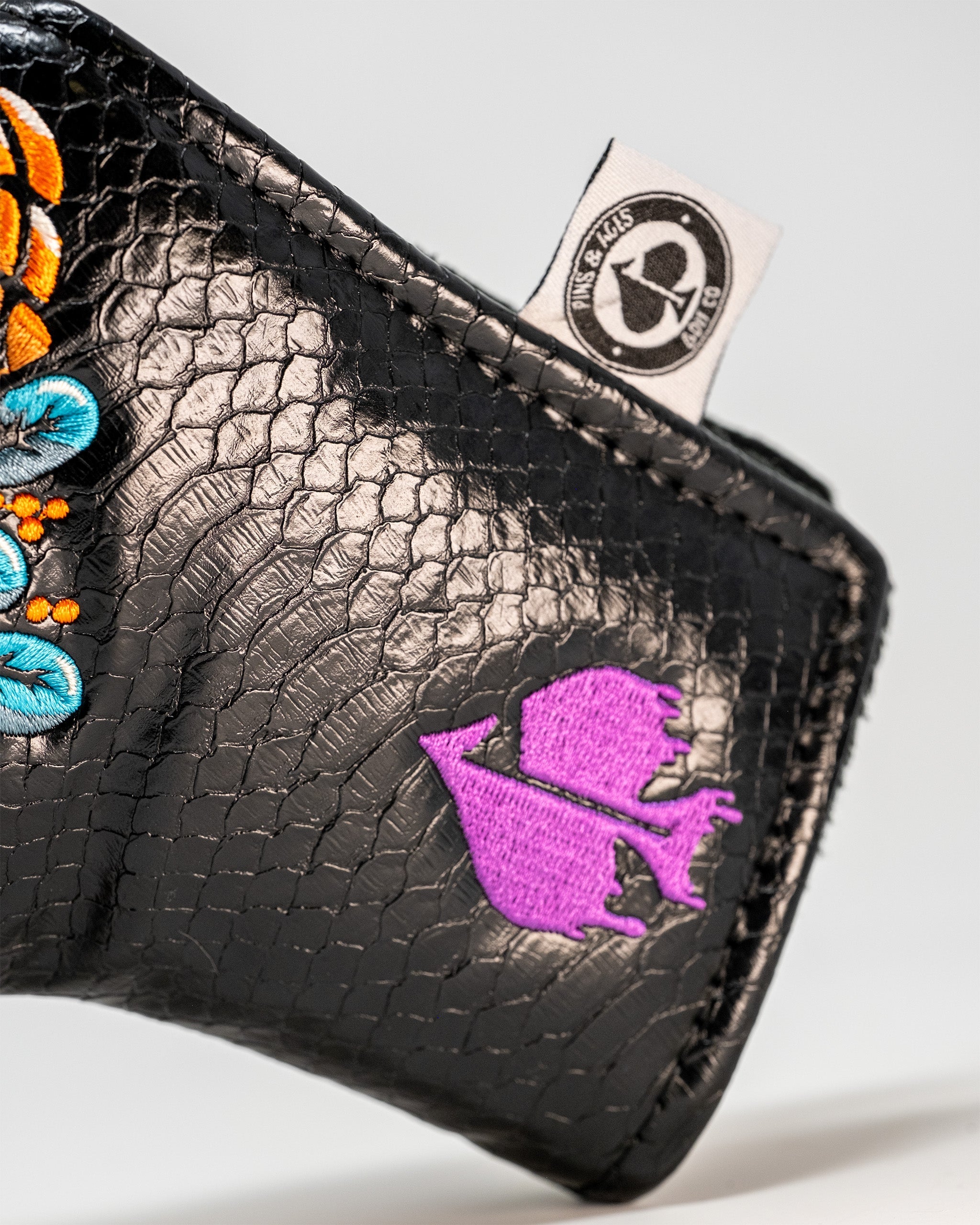 Bold black Venom Blade putter cover featuring vibrant floral designs and a purple logo, perfect for stylish golfers.
