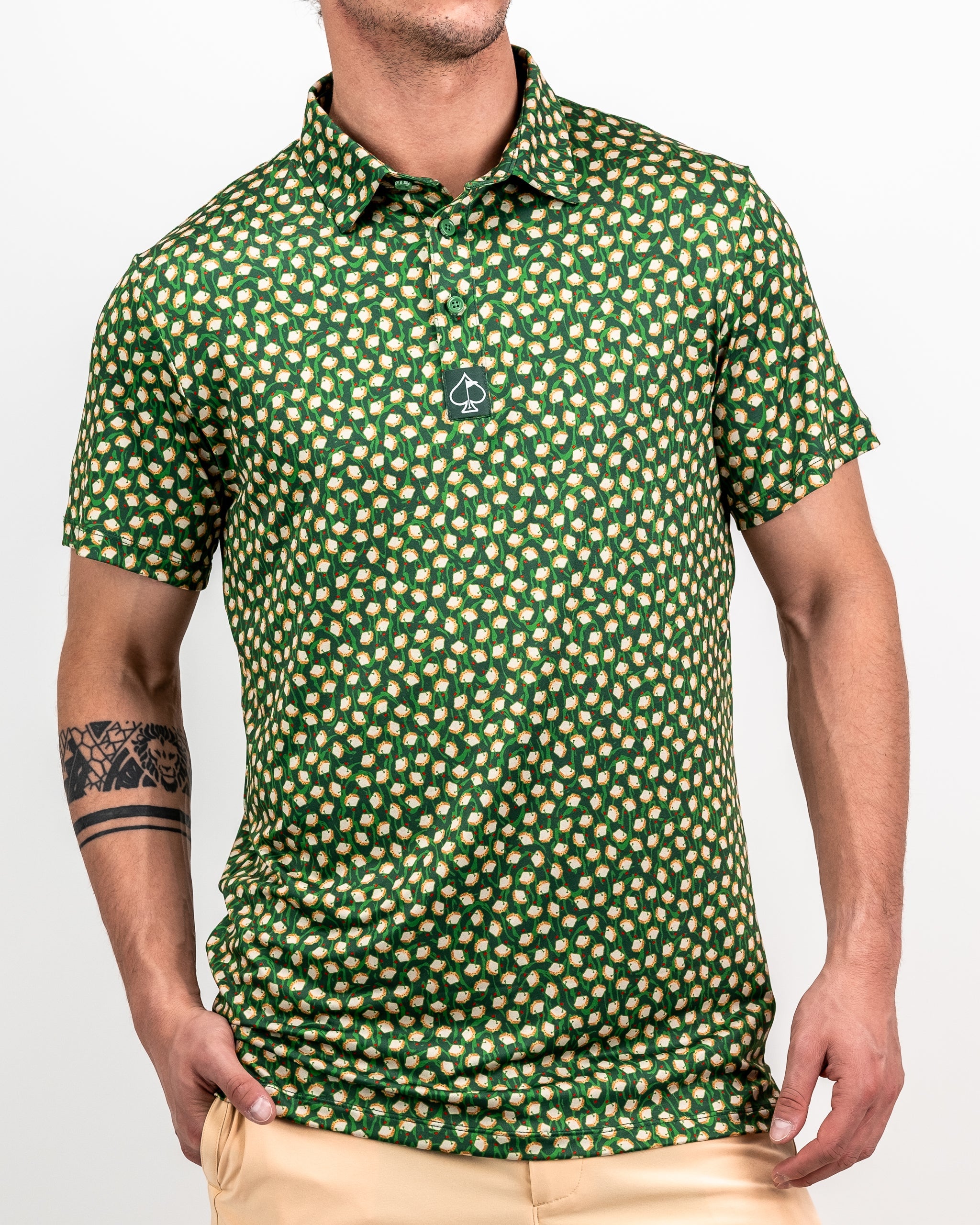Green golf polo with a bold, repeating pattern of white and yellow golf balls, featuring a black spade logo on the chest.