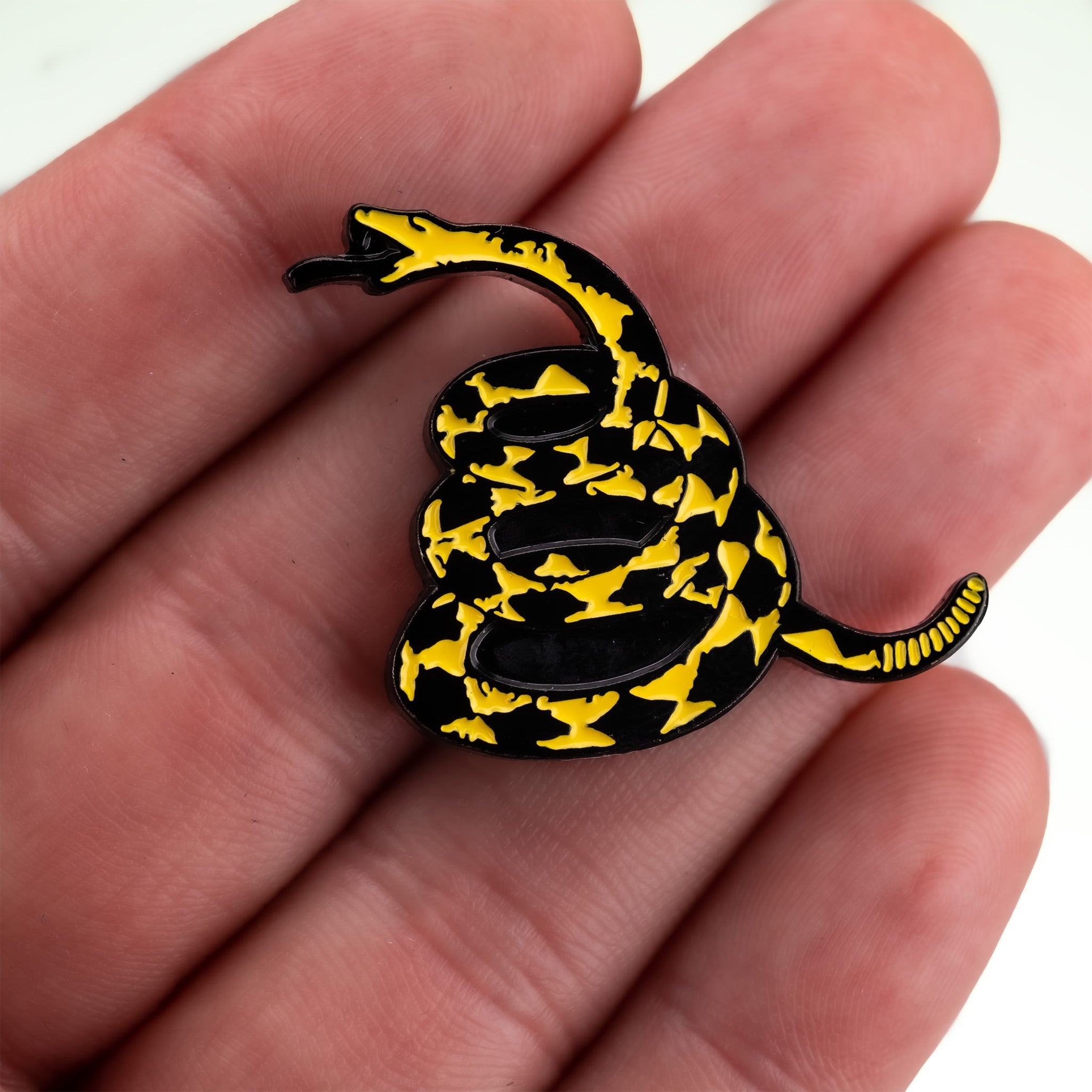 "Don't Tread on Me ball marker held in a hand, featuring a yellow and black snake design."