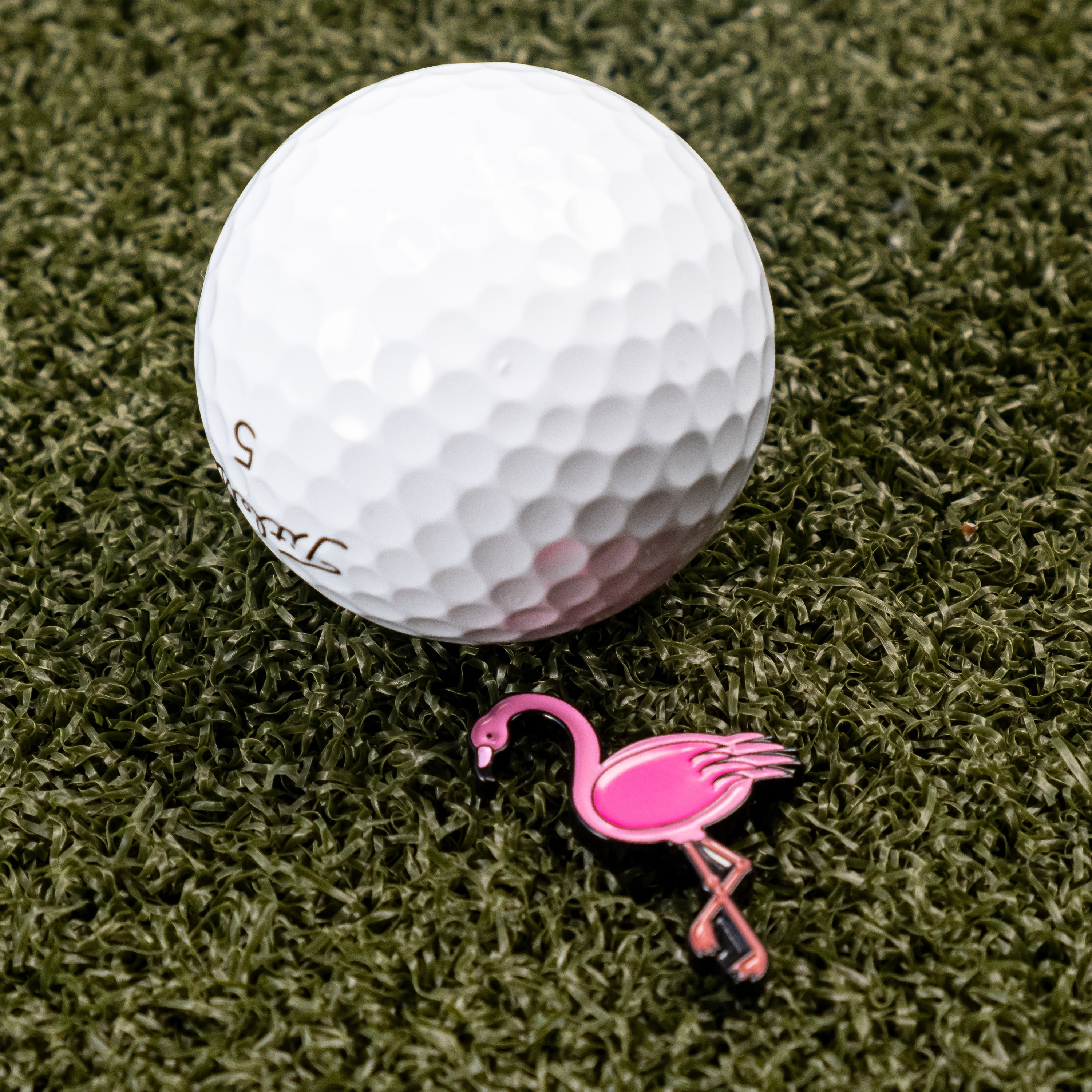 Flamingo-shaped golf ball marker on a golf ball, showcasing vibrant colors and playful design.