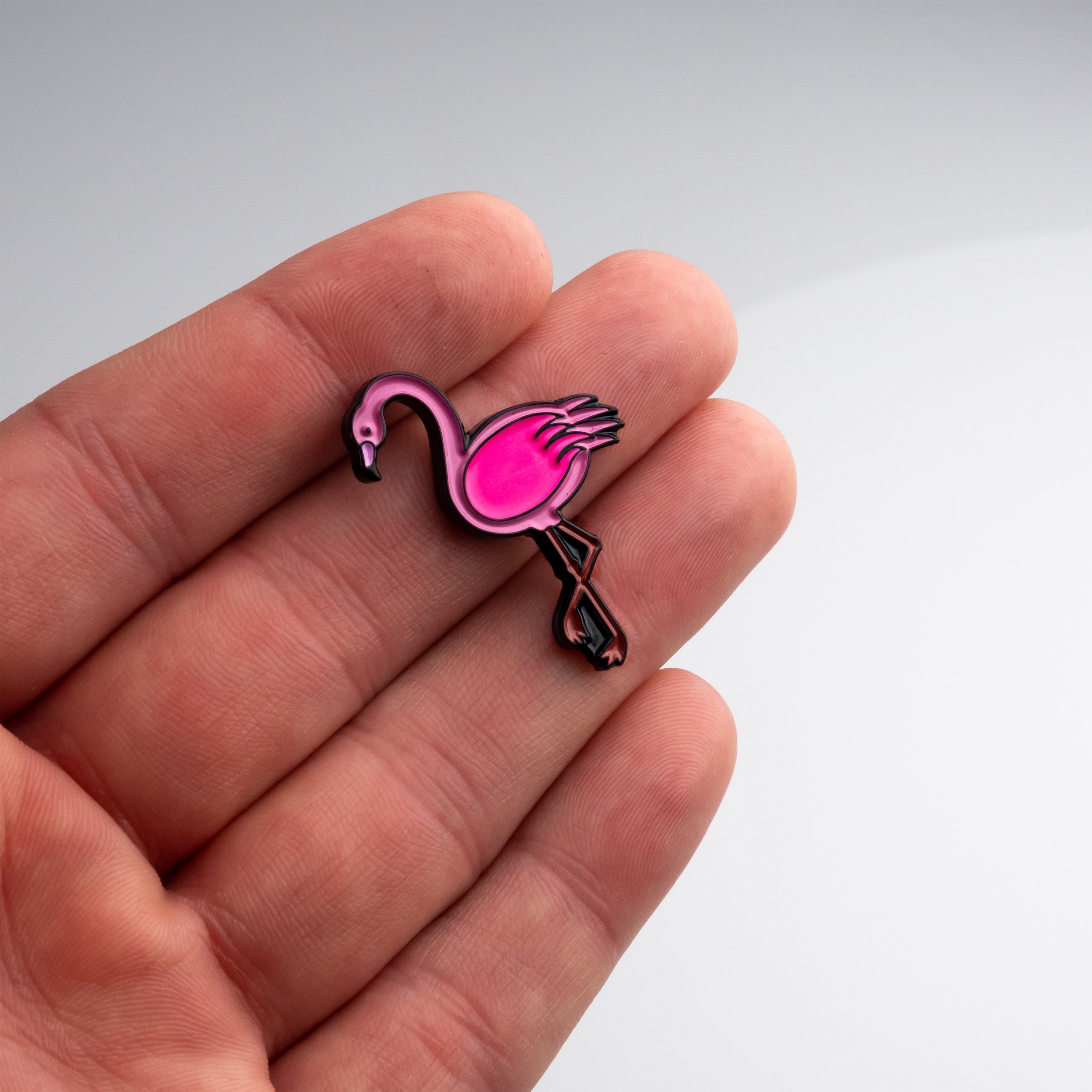 Flamingo-shaped golf ball marker held in hand, featuring vibrant pink color and detailed design.