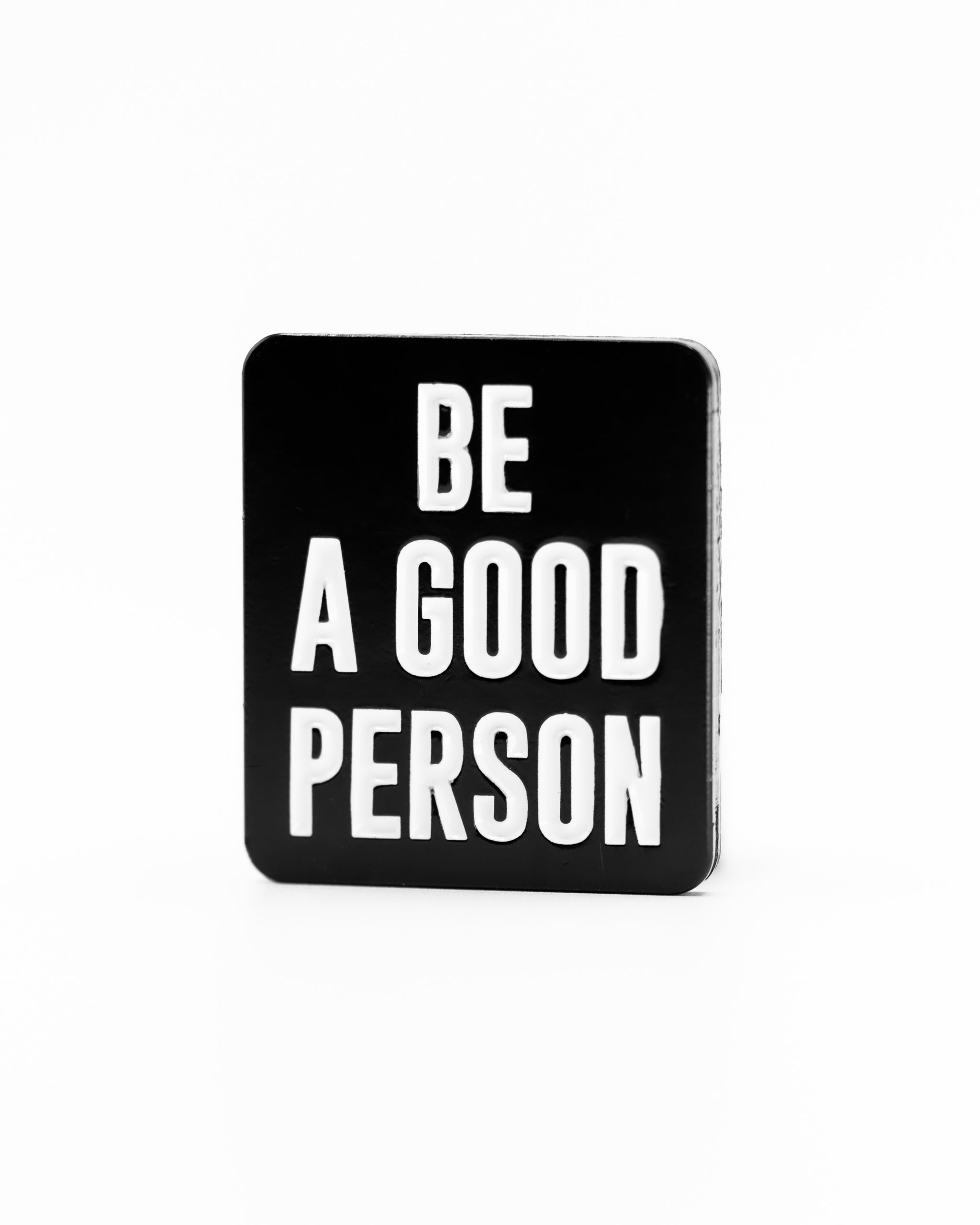 Black square ball marker featuring the phrase "Be A Good Person" in bold white letters, promoting positivity on the golf course.