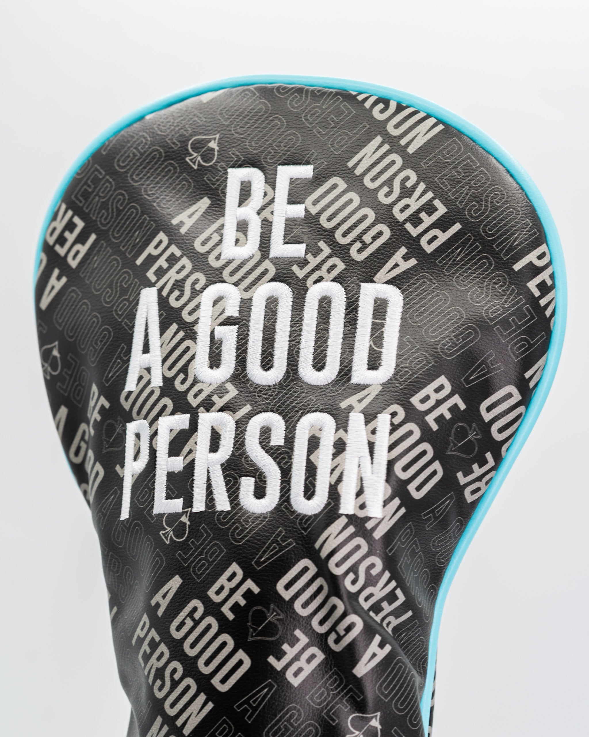 Bold golf driver cover featuring the phrase "Be A Good Person" in a stylish, repeating pattern on a sleek black background.