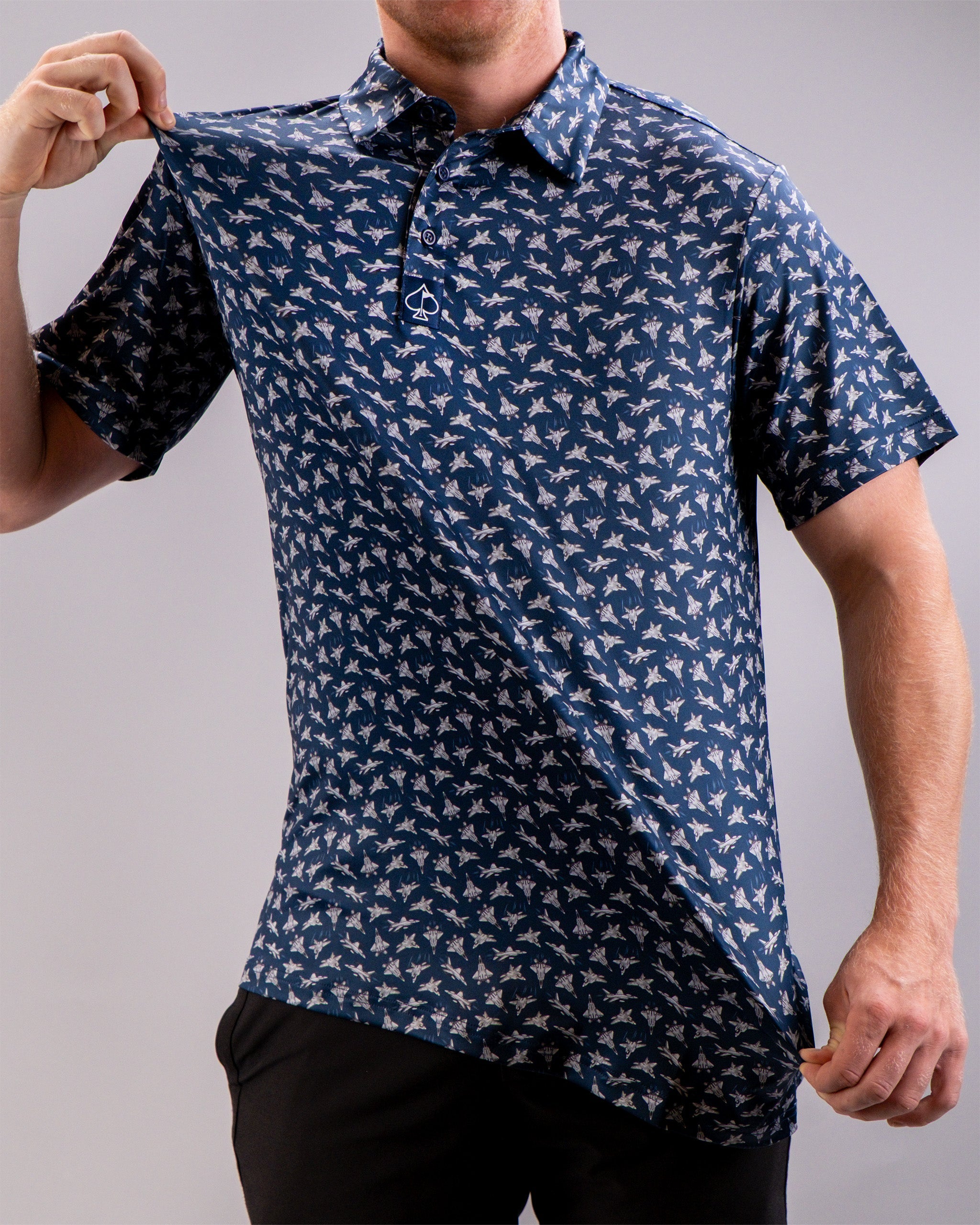 A man wearing a navy blue golf shirt with a white bird pattern, holding the shirt's collar away to show the design.