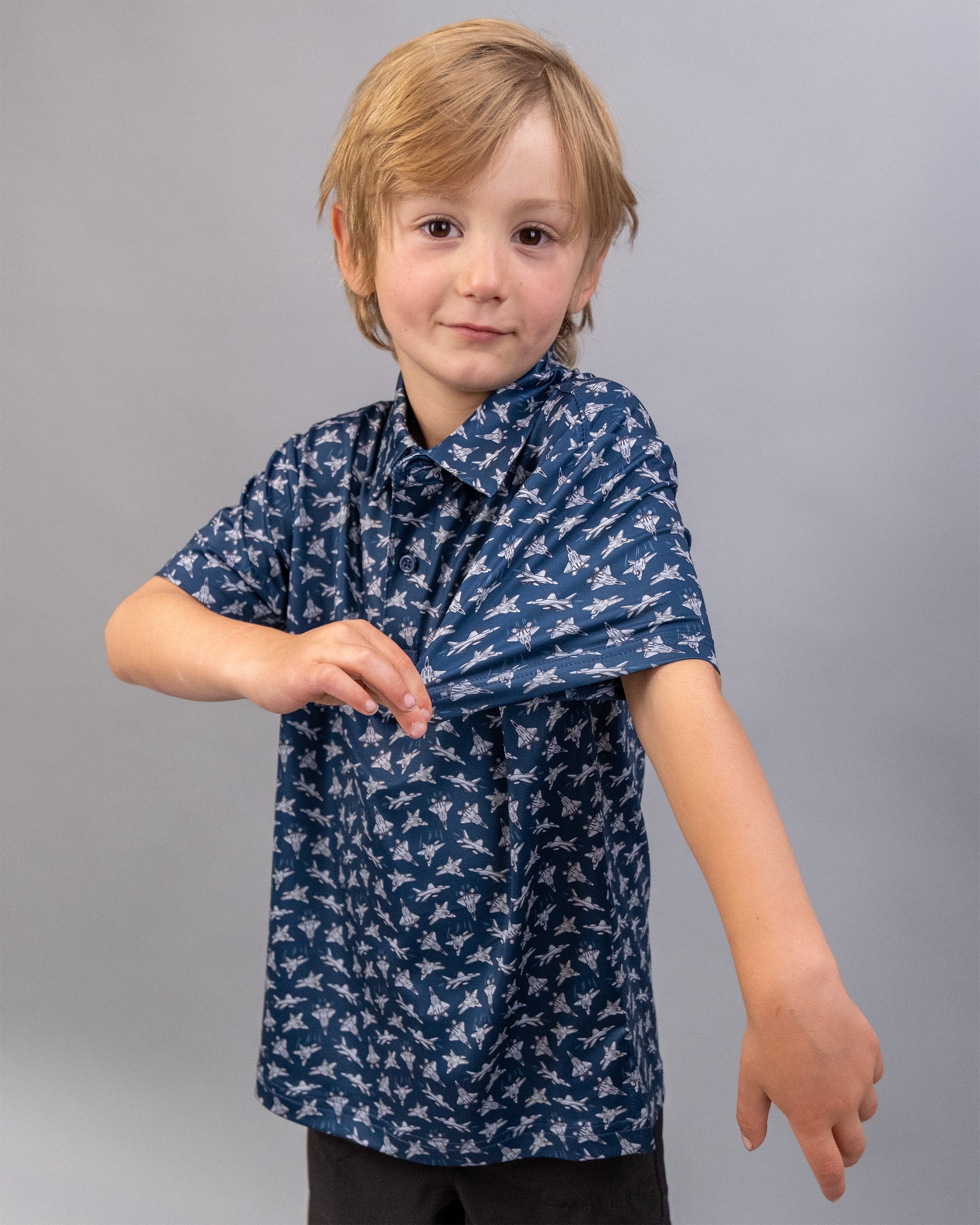 Young boy wearing a blue shirt with a bird pattern, showing off a tattoo of a bird of steel on his arm.