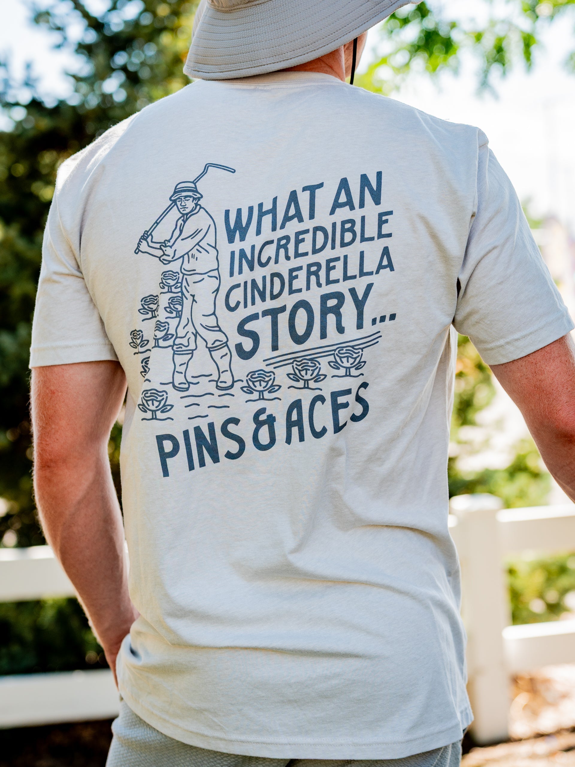 Light beige tee shirt featuring a vintage golfer graphic and the text "What an incredible Cinderella story" on the back.