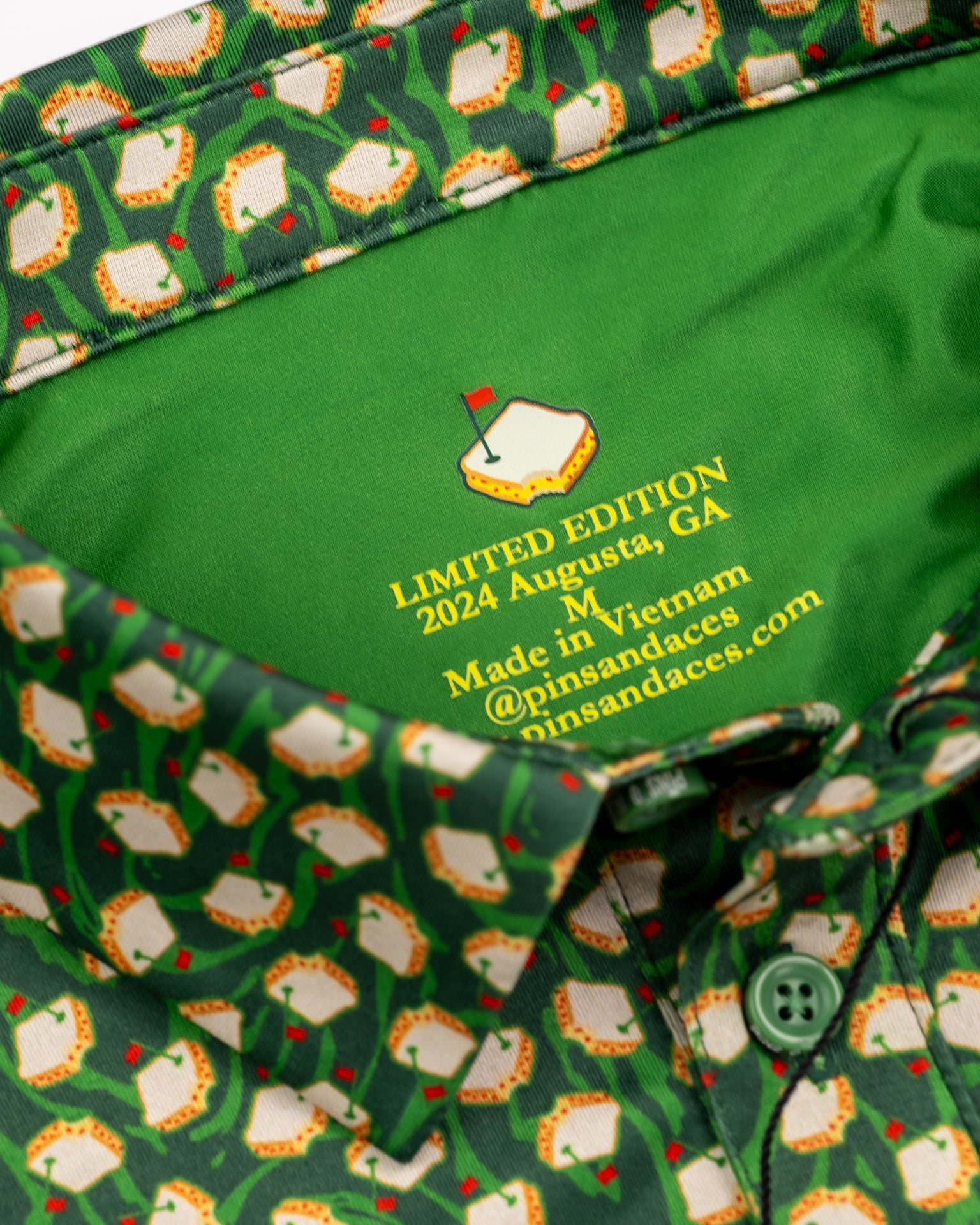 Green golf shirt with a repeating pattern of white golf course flags and red accents, featuring a bold, colorful interior ...