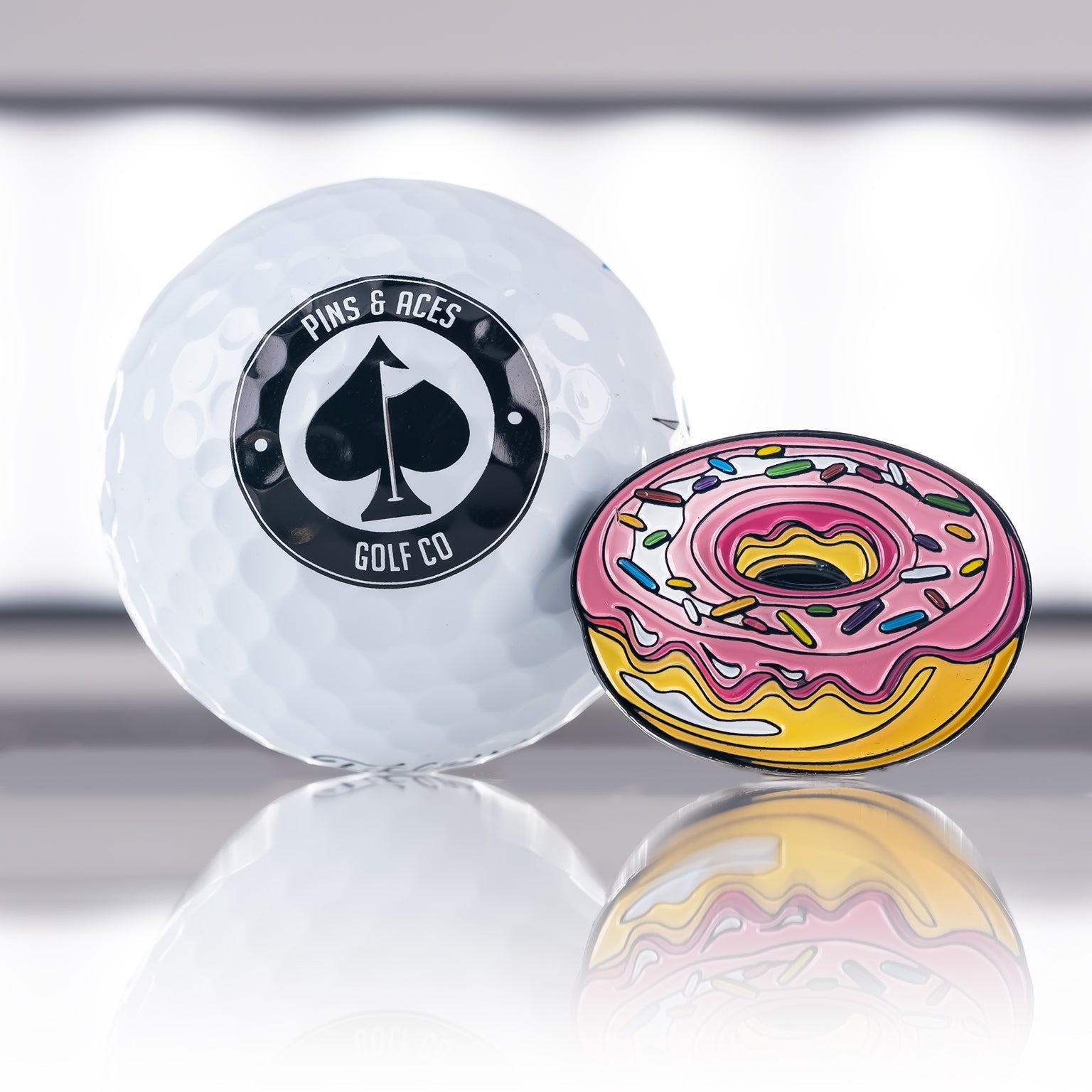 Colorful donut-shaped golf ball marker with a reflective surface.