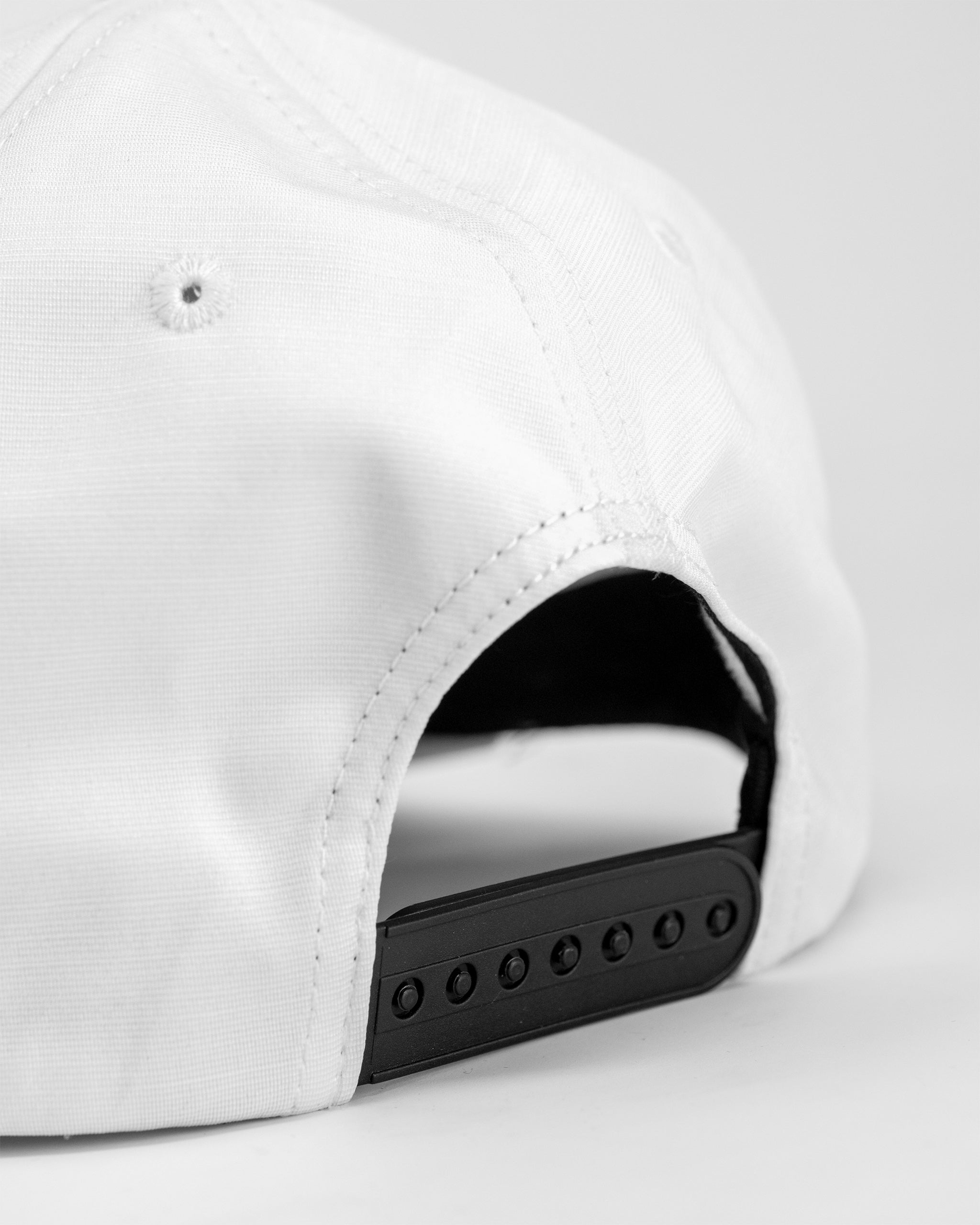 Performance Spade Hat in white, featuring a sleek design and adjustable strap, perfect for outdoor activities.