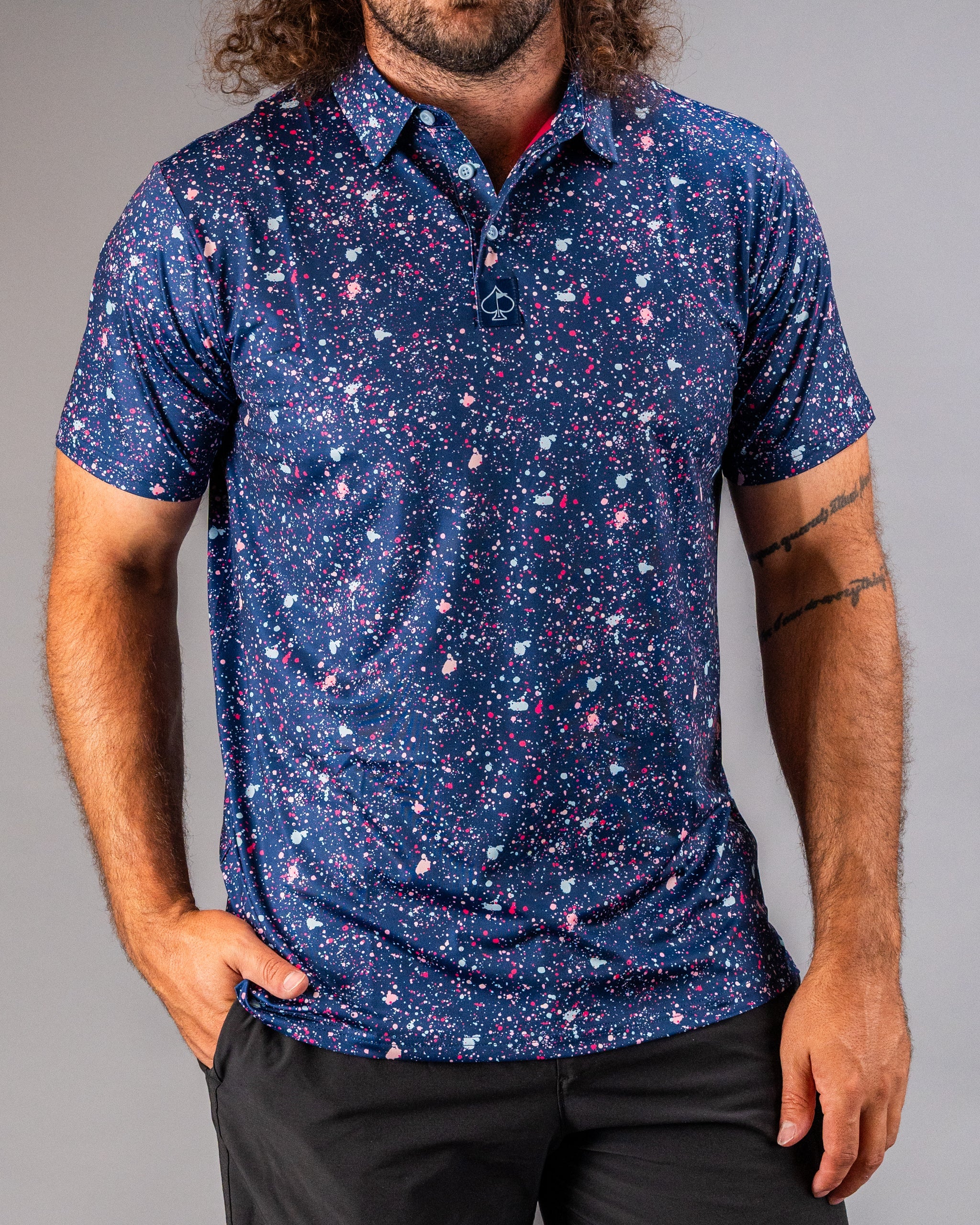Men's blue golf polo featuring a vibrant splatter design in pink and white, perfect for making a bold statement on the course.