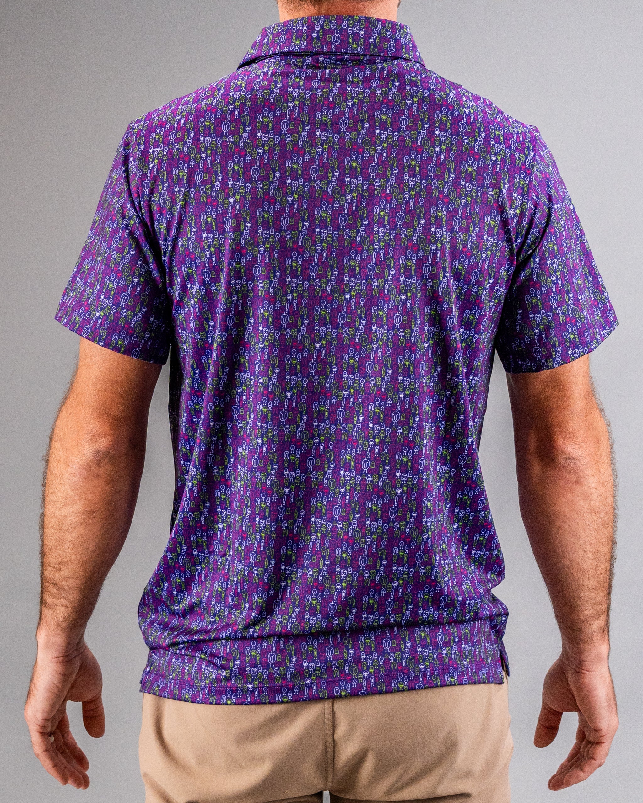 Back view of a golfer wearing a vibrant purple shirt with a colorful, bold golf-themed pattern featuring golf clubs and ba...