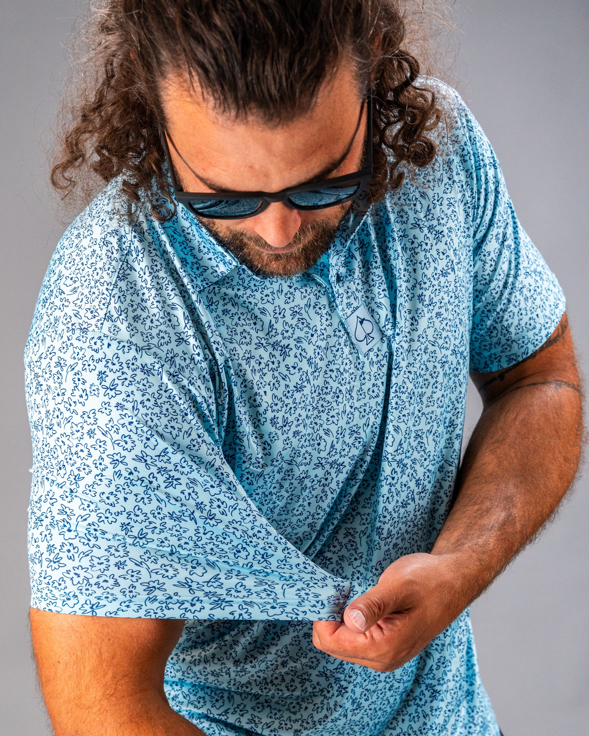 Men's blue golf shirt featuring a flower doodle pattern, designed for a stylish and bold look on the course.
