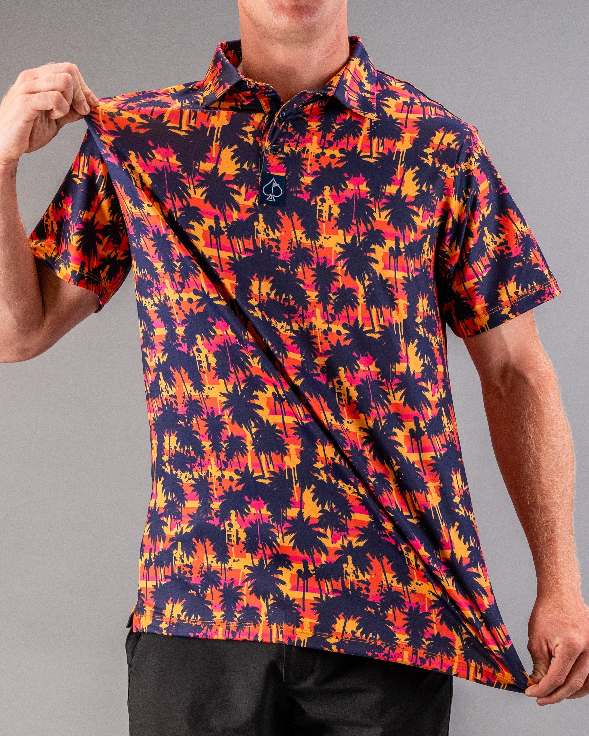 Bright tropical print polo shirt with orange, pink, and navy palm trees, perfect for bold golf style.