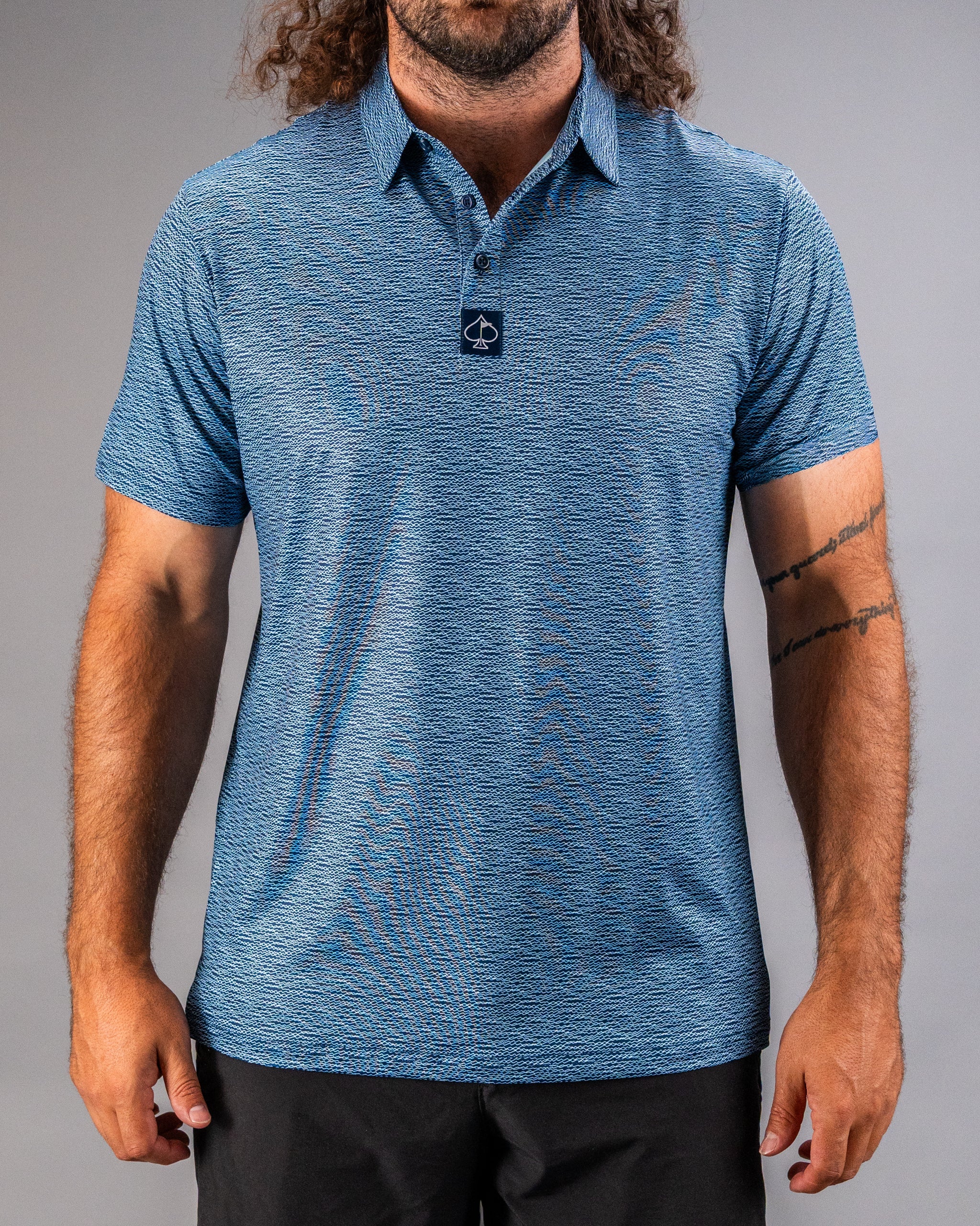 Men's blue golf polo shirt featuring a textured squiggle pattern and a logo on the collar, perfect for stylish play on the course.