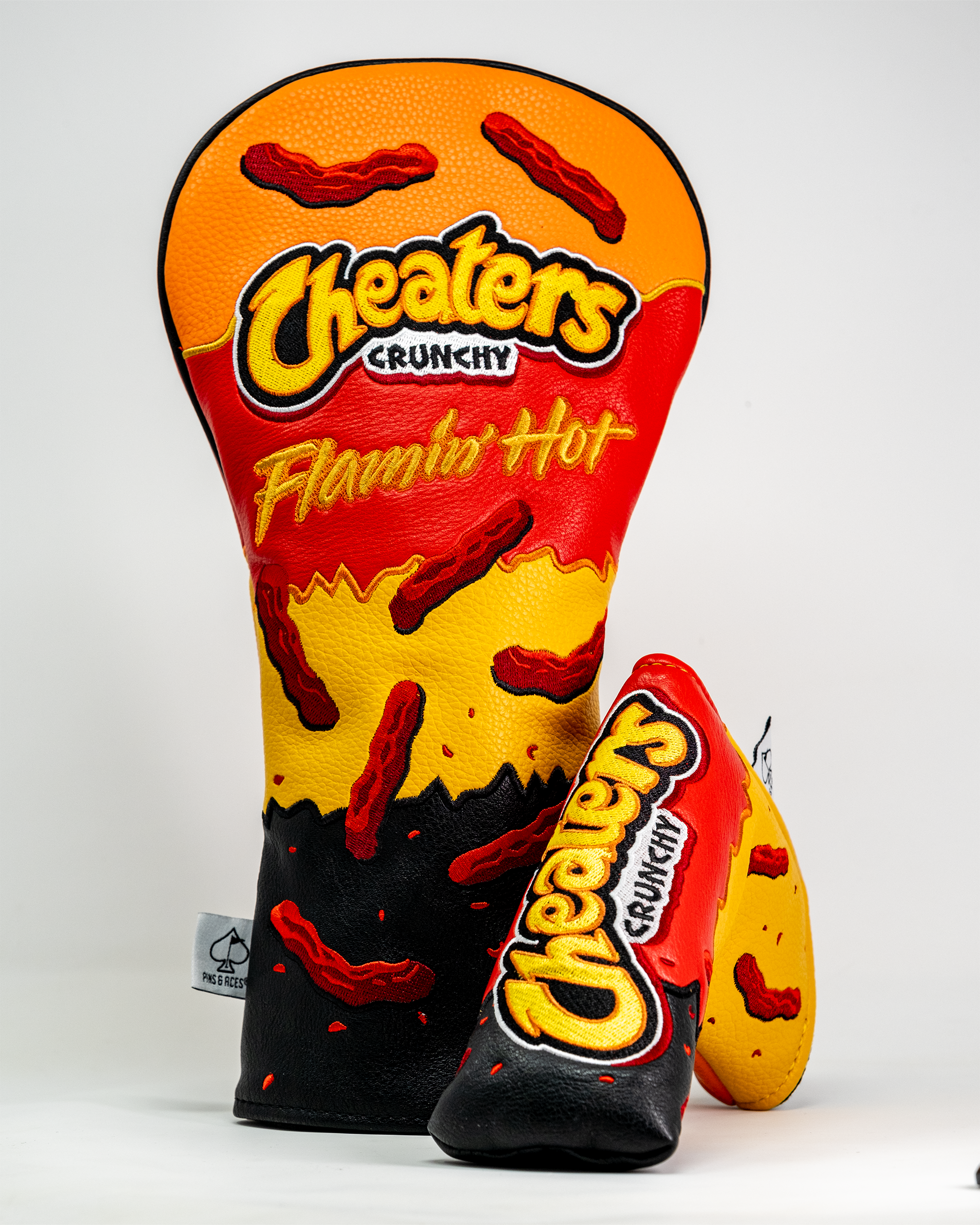 Golf driver cover designed to resemble Flamin' Hot Cheeters snack packaging, featuring bold red, yellow, and black colors with chili pepper graphics.