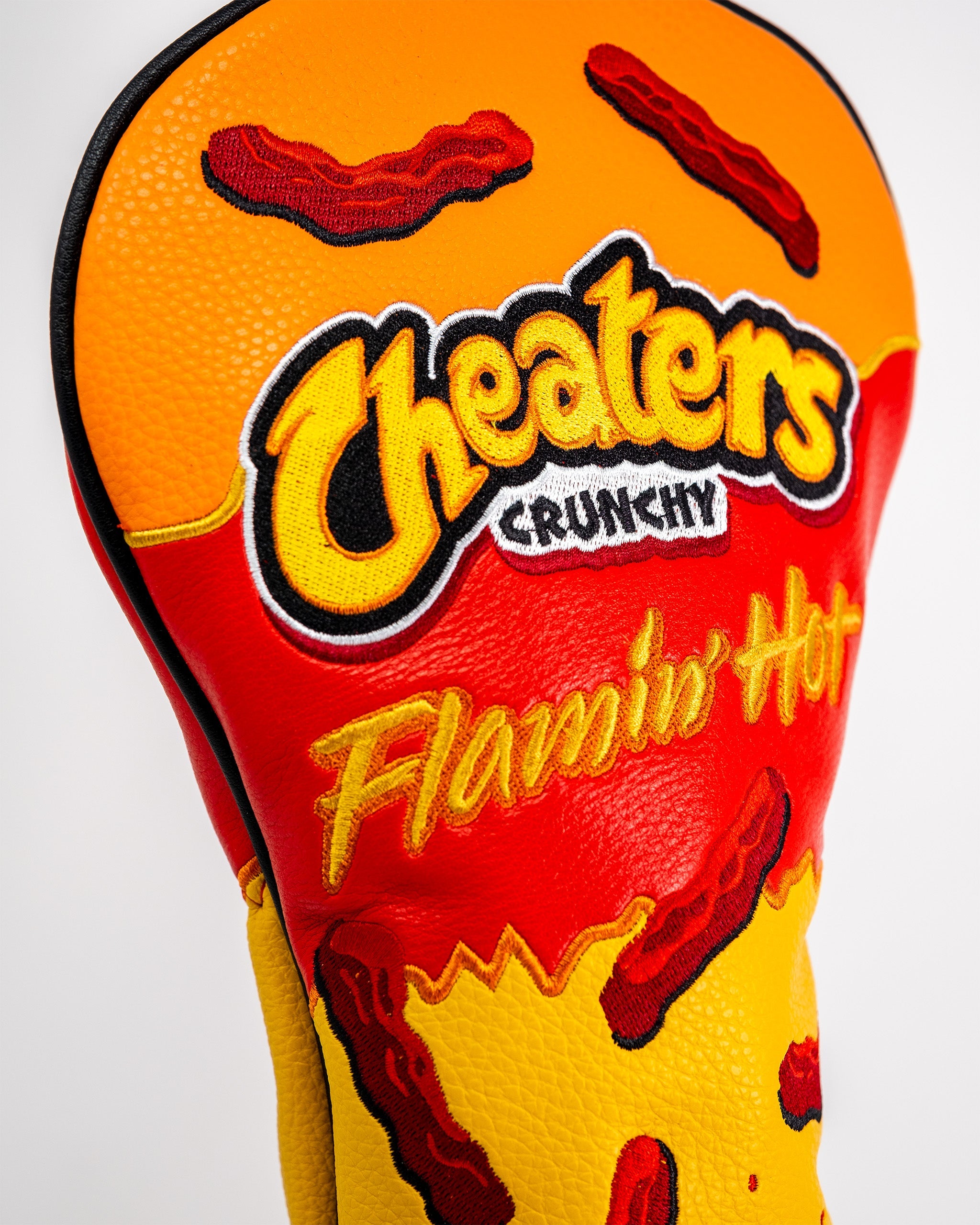 Golf driver cover featuring a fiery Flamin' Hot Cheaters design with bold colors, chili pepper graphics, and playful embroidered text.
