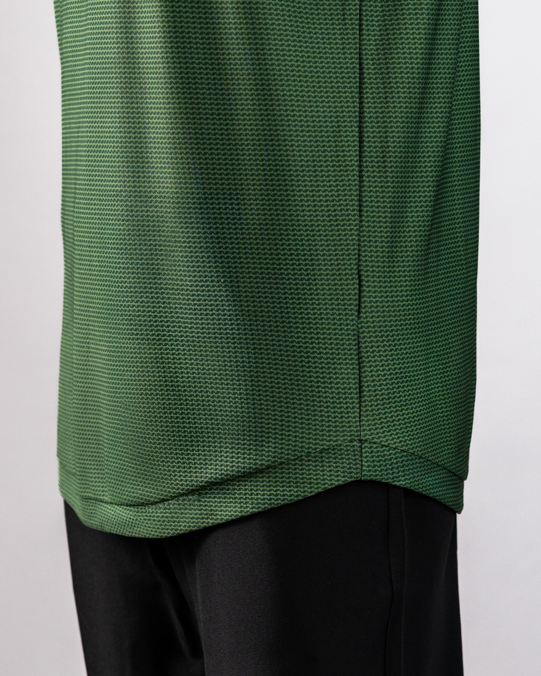 Close-up of a green Player Preferred™ Polo shirt with a forest wave pattern, paired with black pants.
