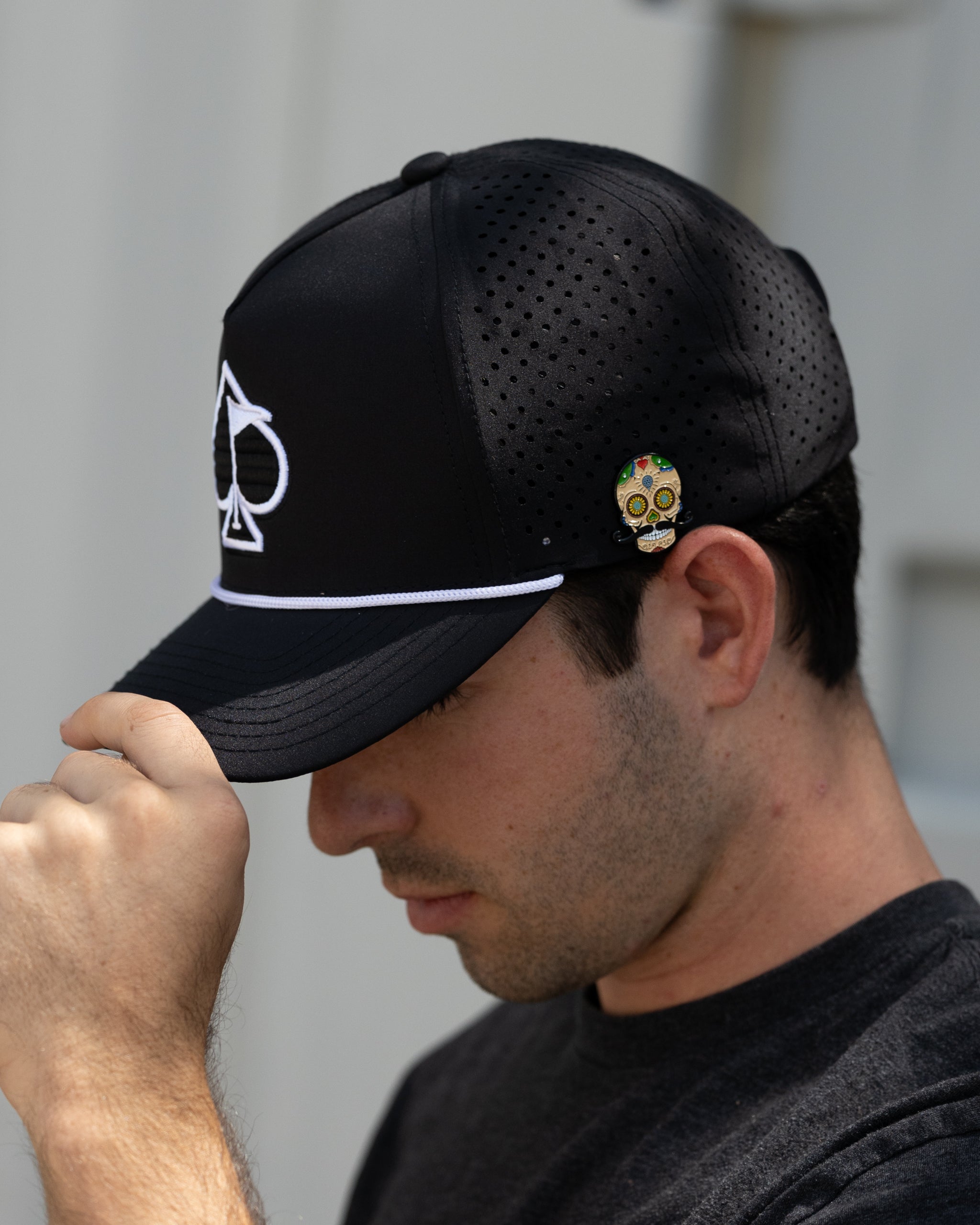Black perforated rope hat with a relaxed fit, showcased in a lifestyle setting.