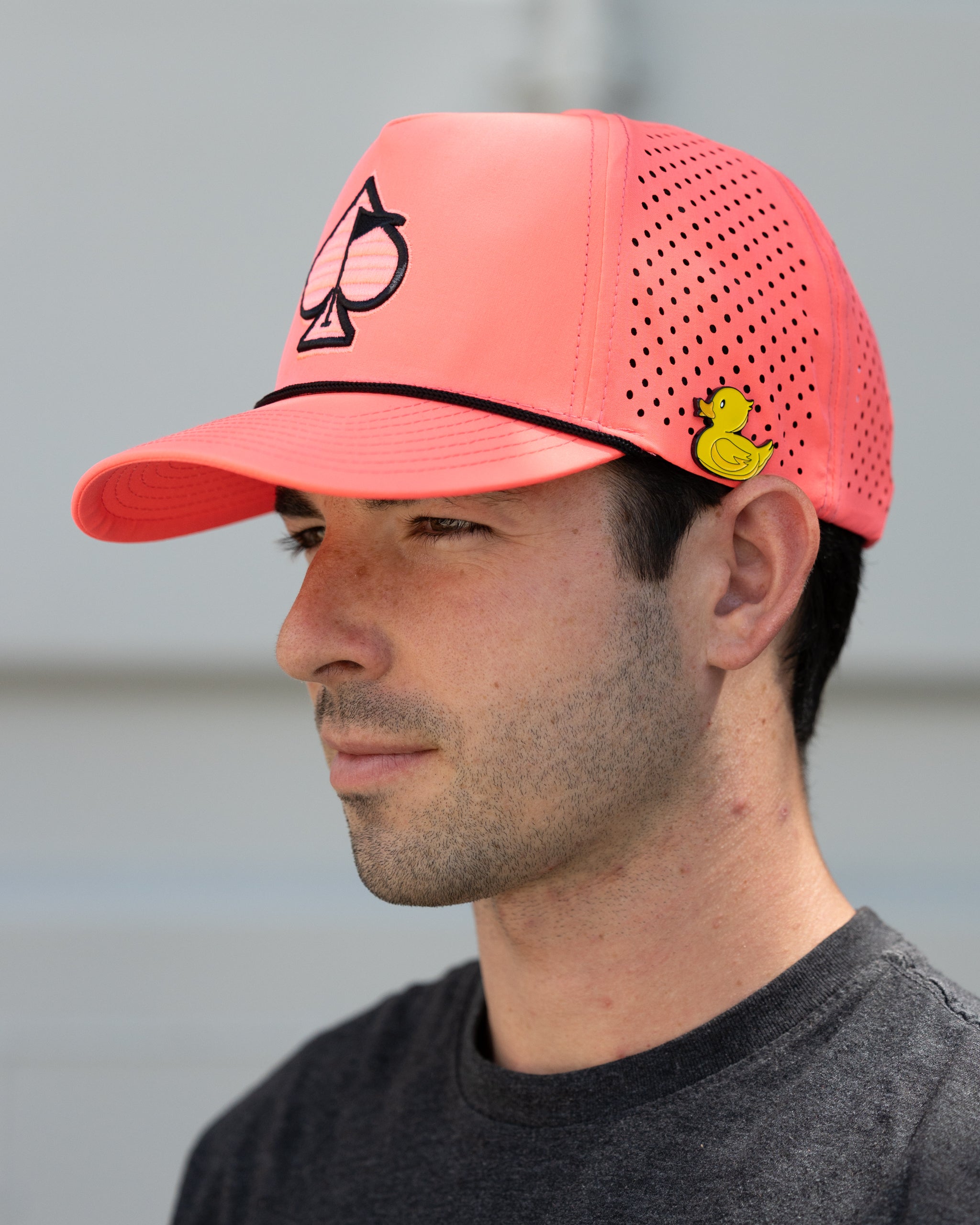 Perforated rope hat in highlighter pink displayed outdoors, showcasing its vibrant color and stylish design.