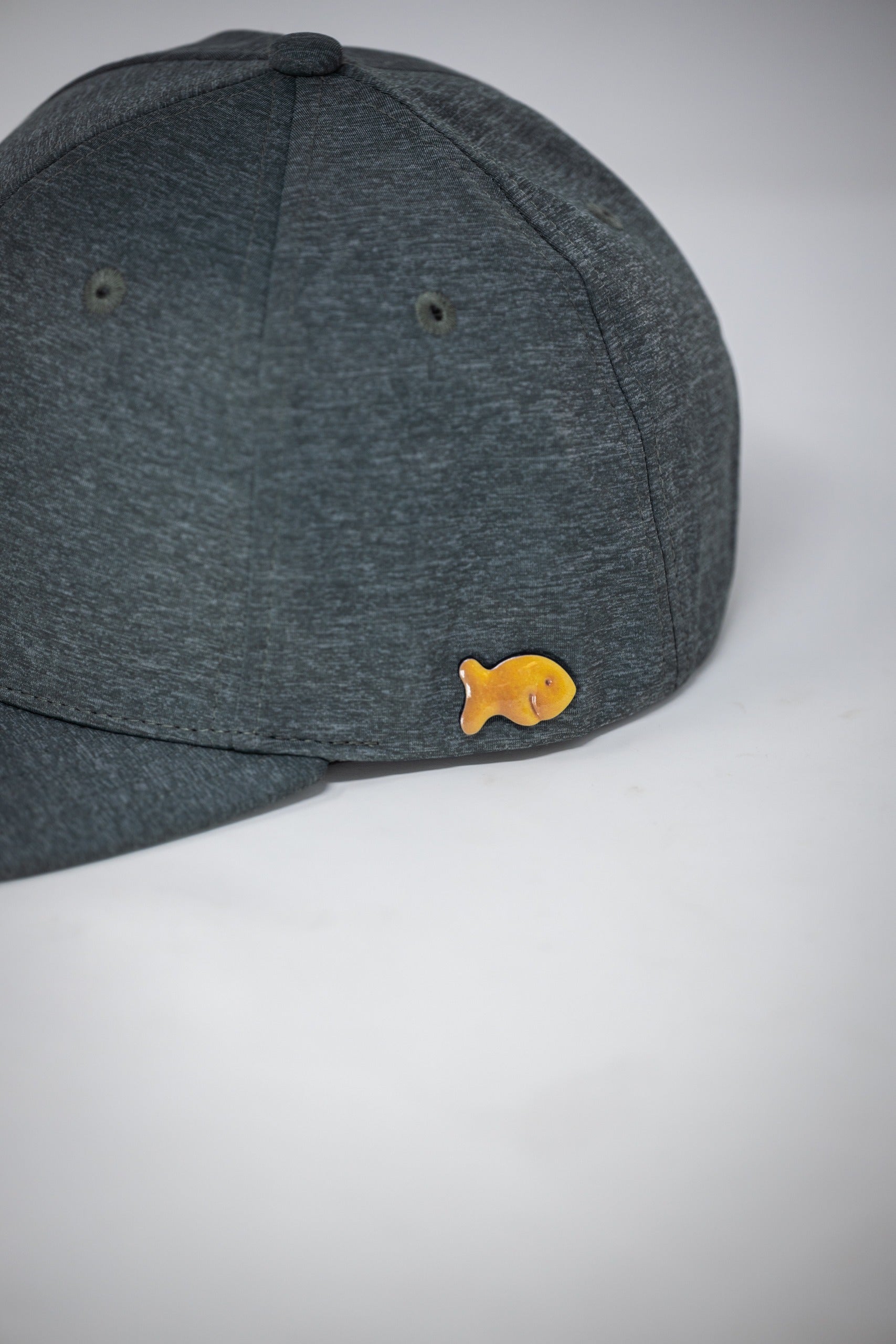 Performance Spade Hat in ash gray featuring a unique fish logo on the side, perfect for stylish golfers.