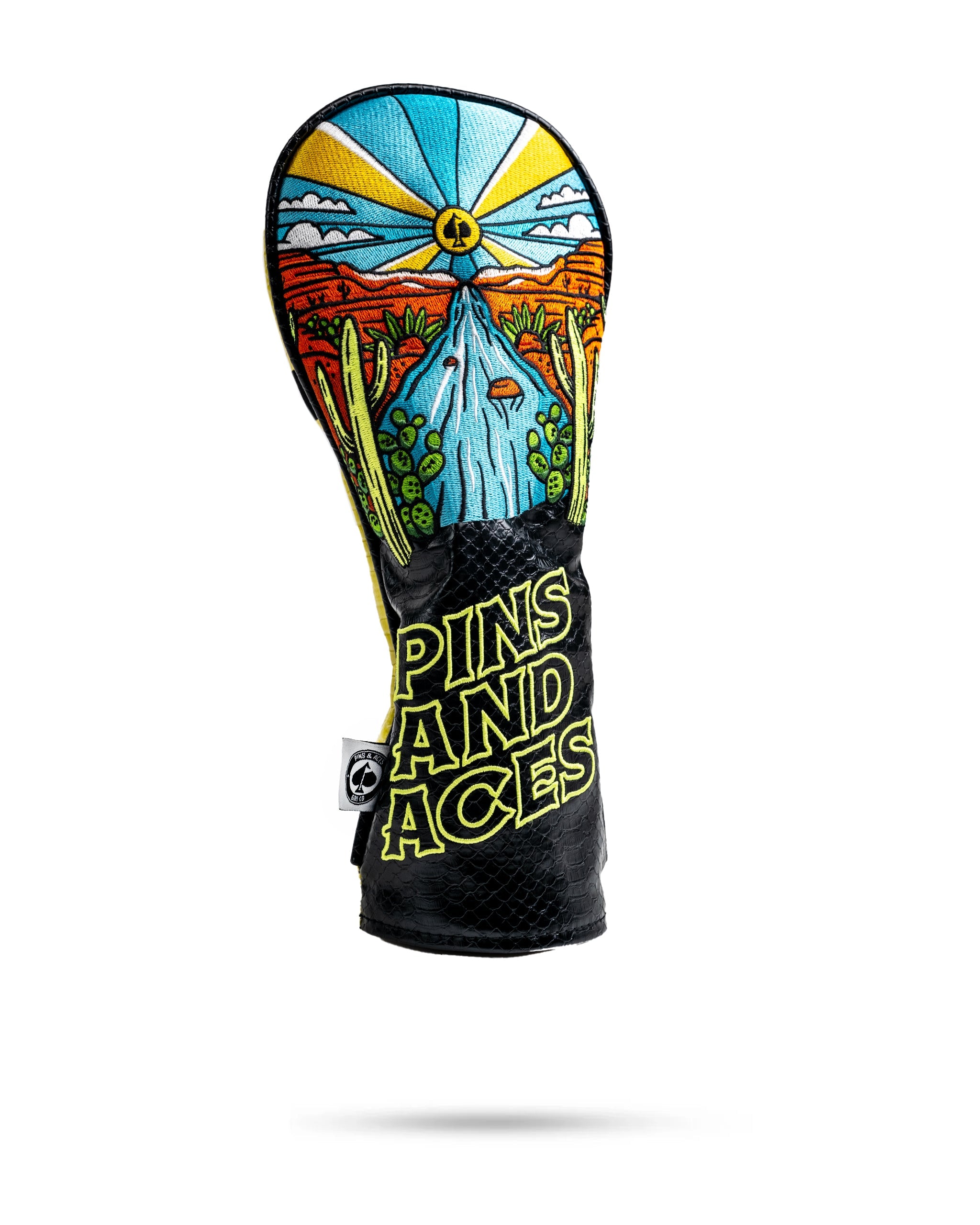 Colorful golf headcover featuring a desert scene with cacti, waterfall, and a bright sun, with "Pins and Aces" text on the...