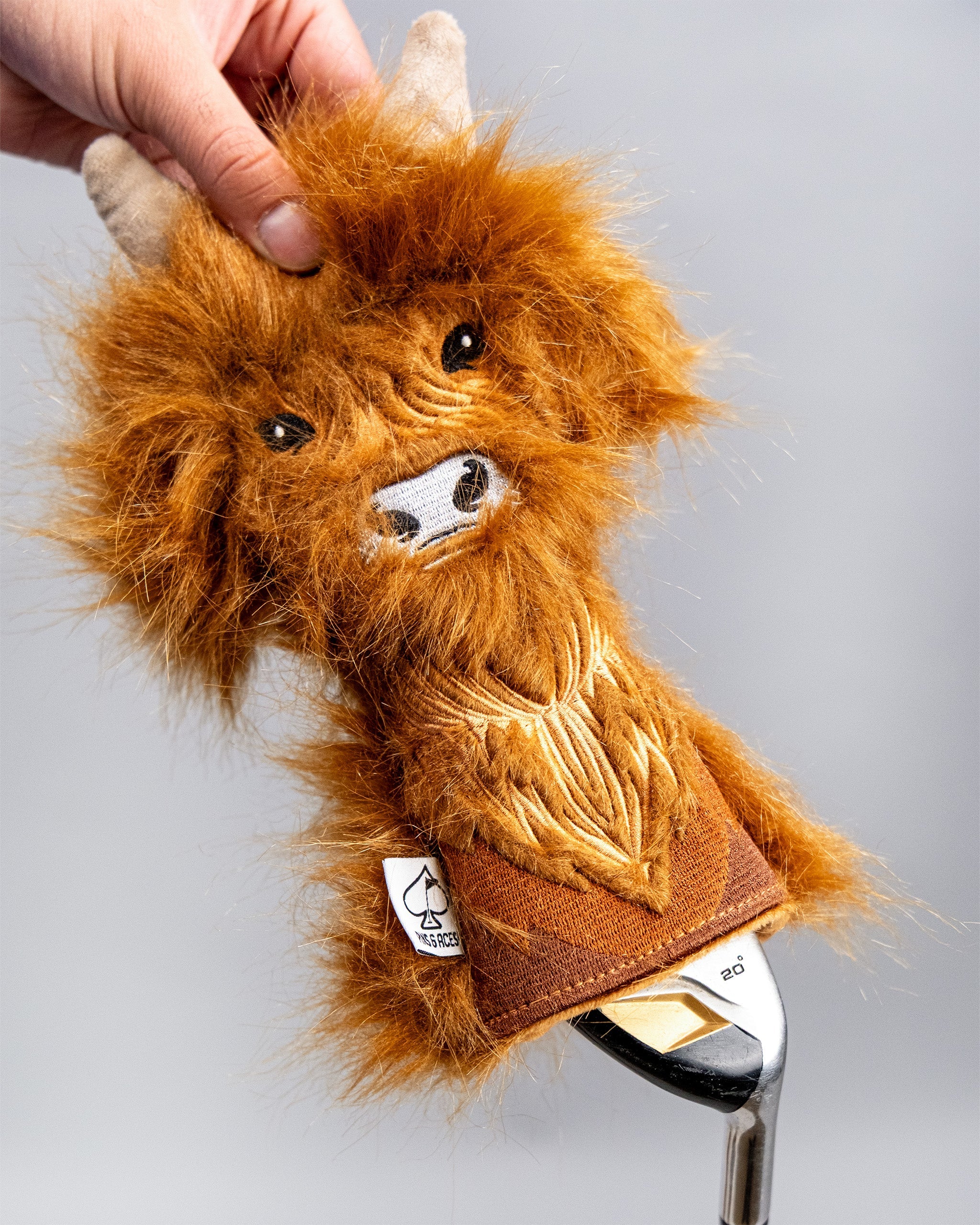 Golf club with a Highland Cow themed hybrid cover featuring a furry, detailed cow face design and warm brown tones.