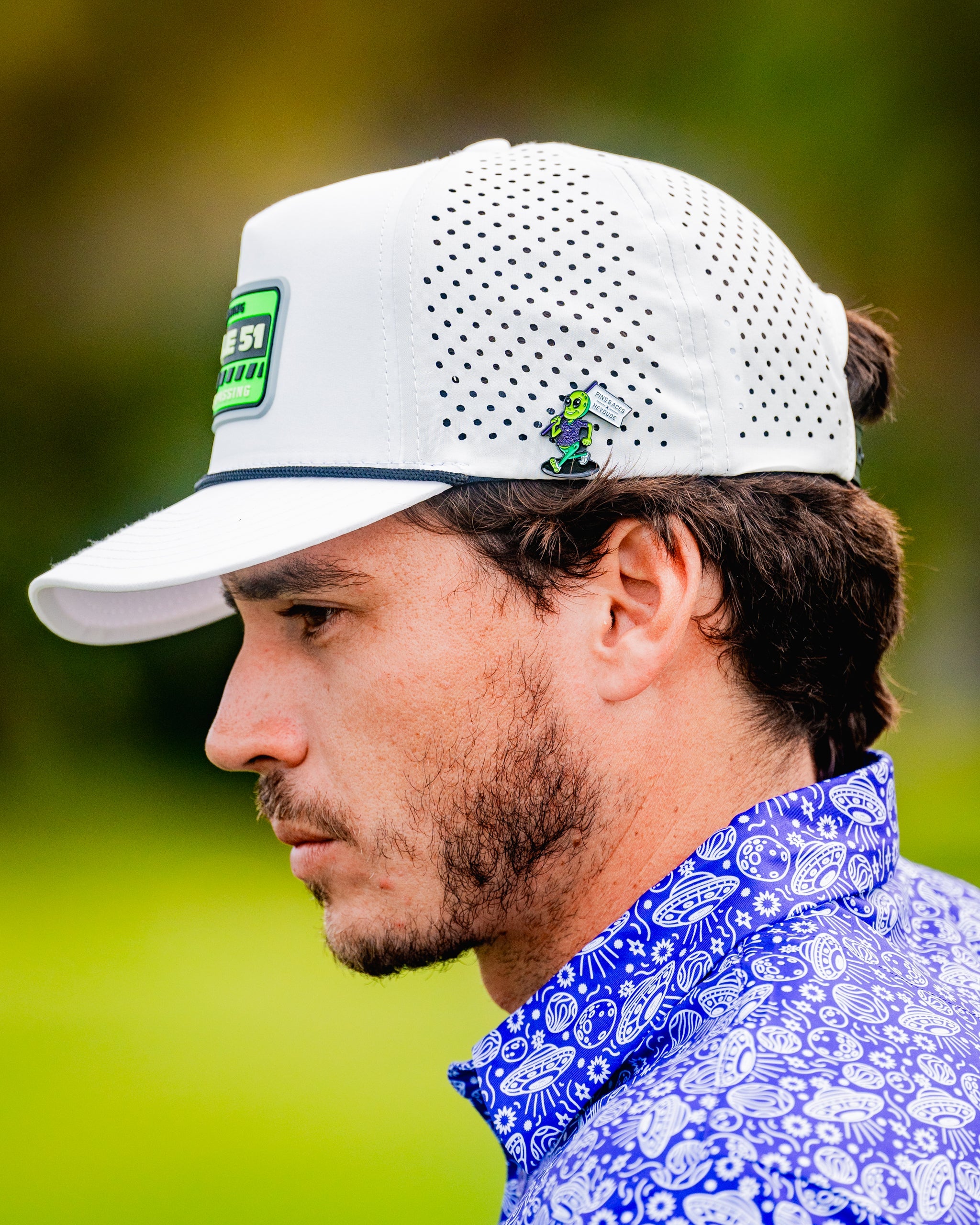 Alt text: HEYDUDE Alien Ball Marker featuring a unique alien design with bold colors on a circular shape, ideal for golf enthusiasts.