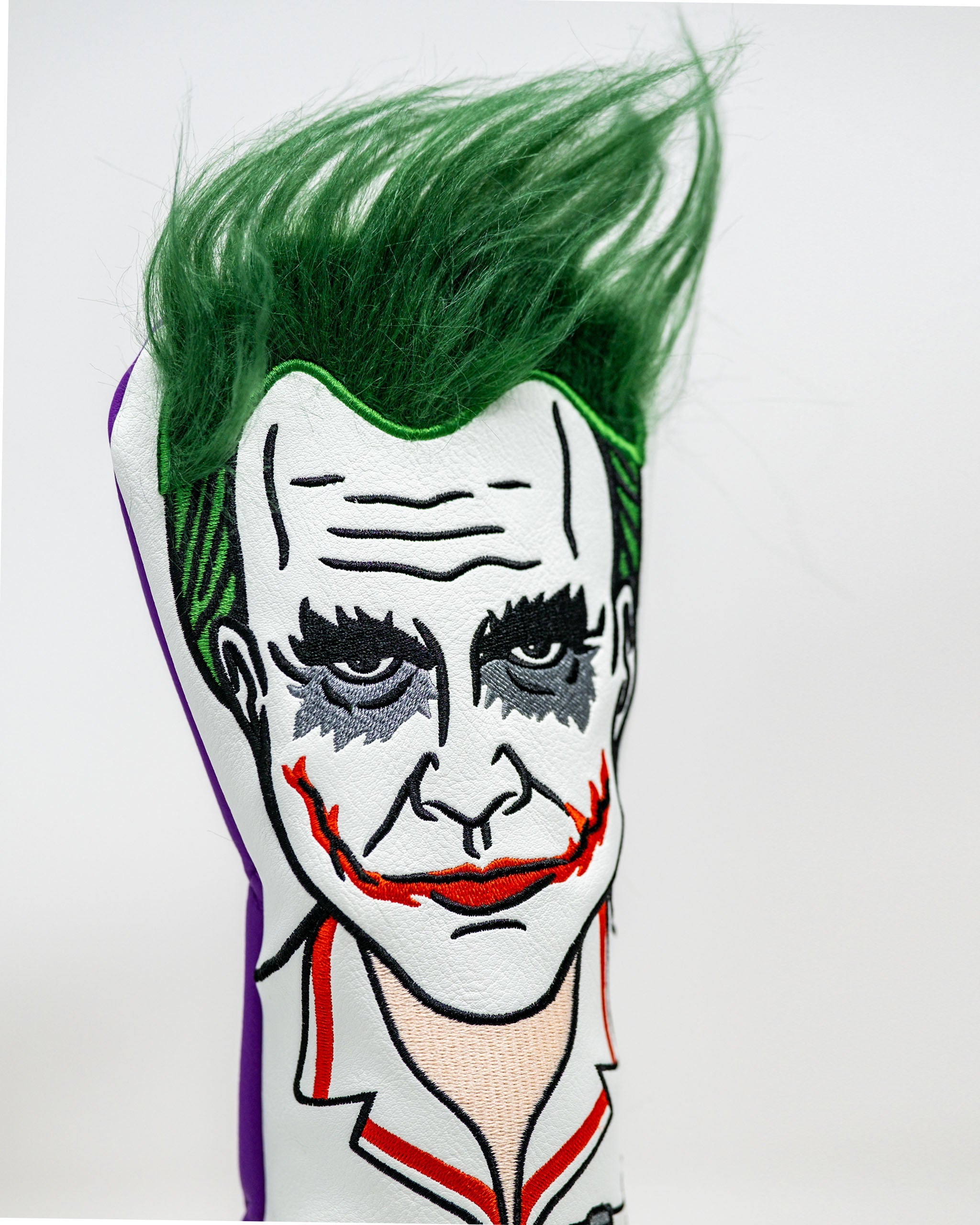 Golf headcover featuring the Joker's face with green hair, gray eyeshadow, red lips, and a white collar, bold and unique d...
