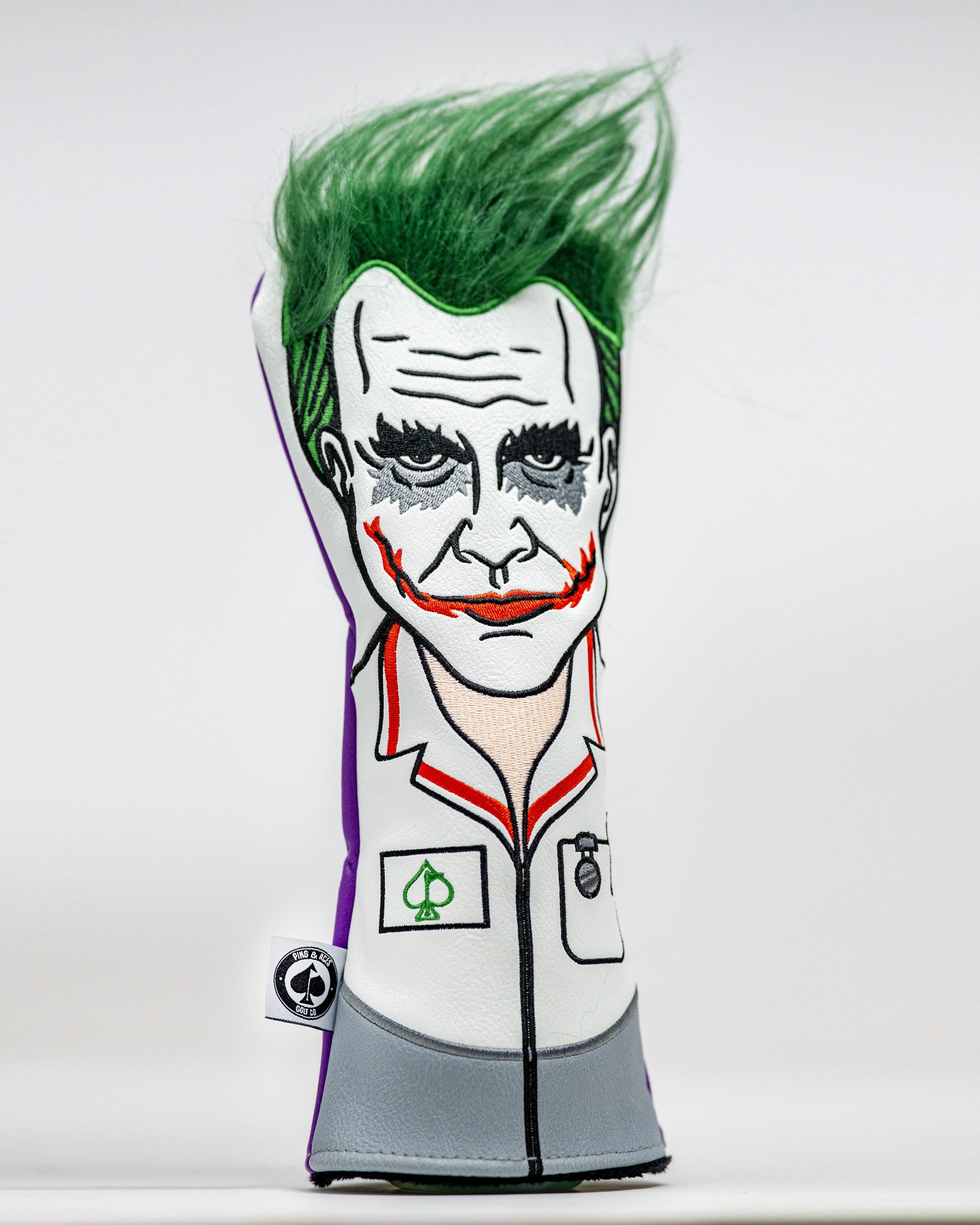Golf headcover featuring a Joker-inspired face with green hair, dark makeup, and a white jacket, perfect for bold golfers.