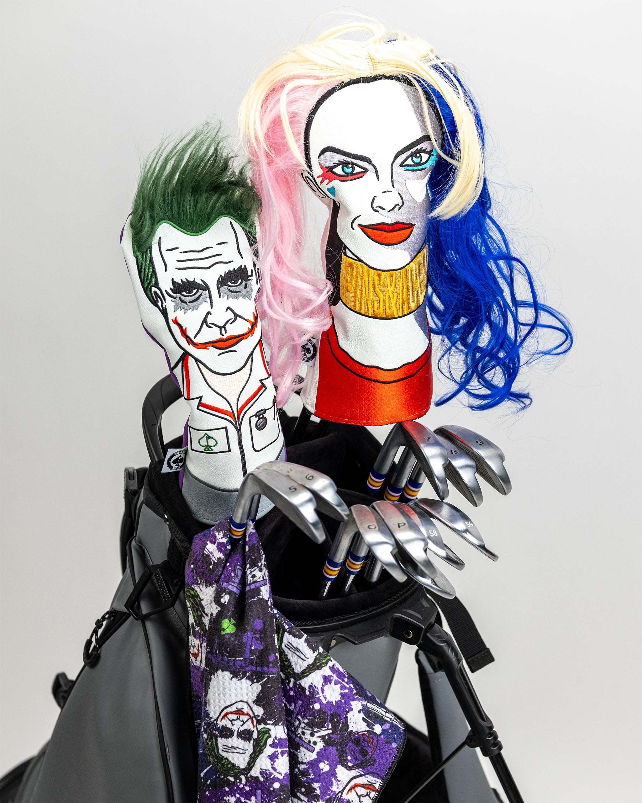 Colorful Joker and Harley Quinn headcovers with bold, comic-inspired embroidery on a golf bag with clubs.