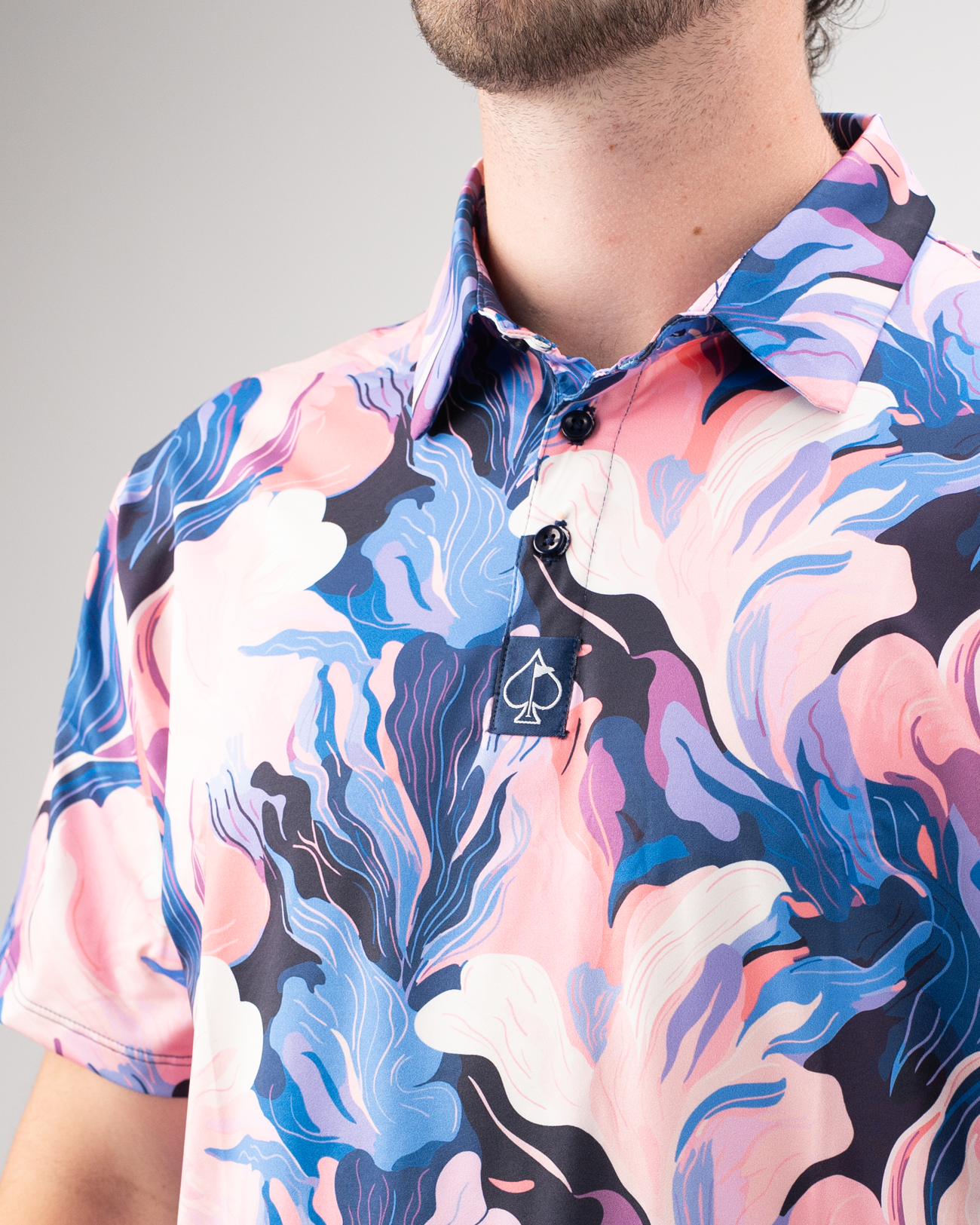 Men's golf polo shirt featuring a vibrant melting floral pattern in pink, blue, and white hues for a bold look on the course.