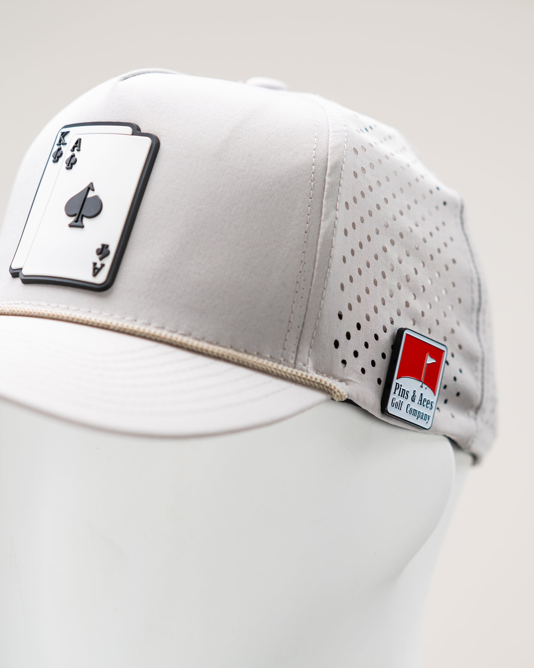 Perforated Rope Hat in Bone color with an AK logo, featuring a stylish design and adjustable fit.