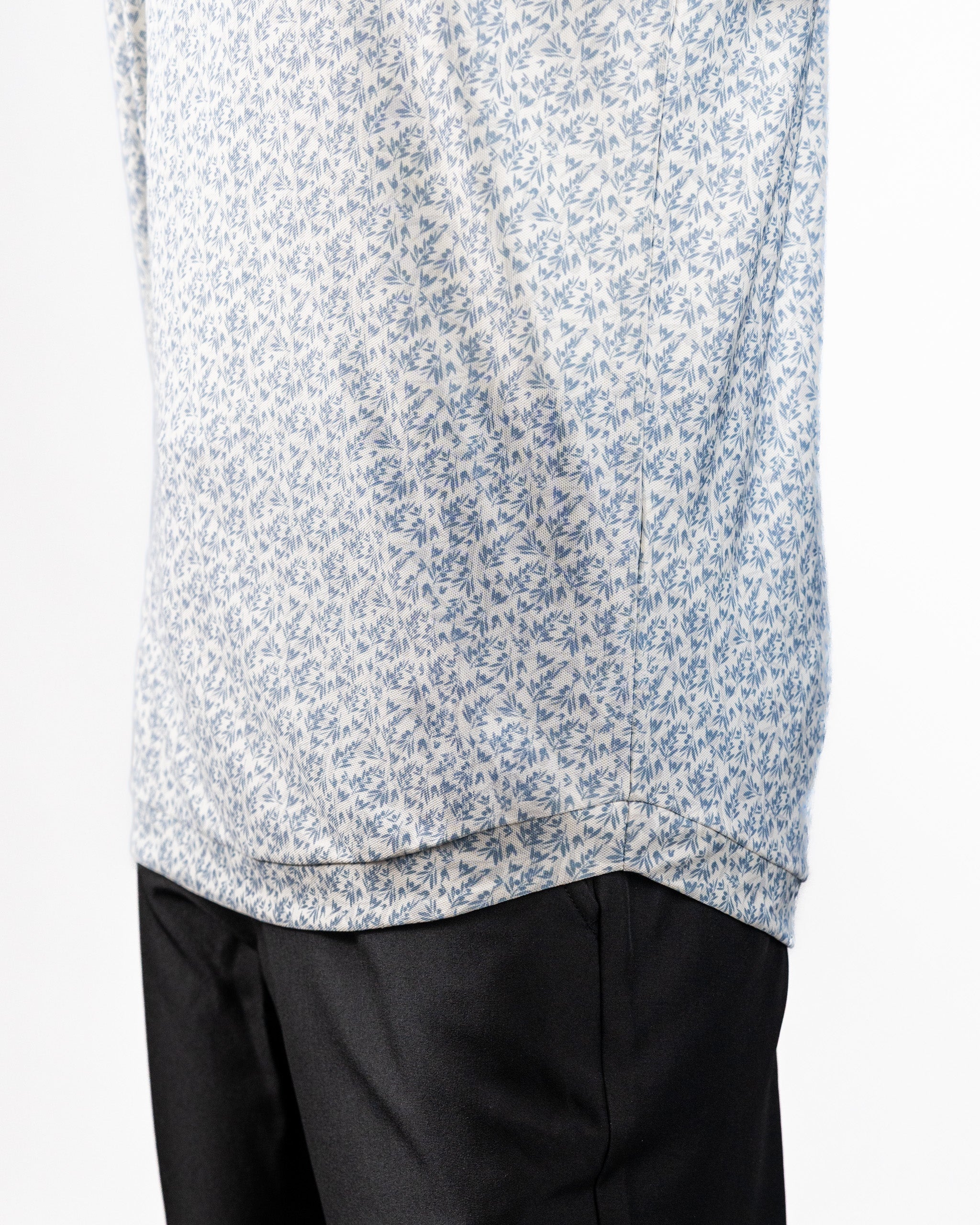 Close-up of a Player Preferred™ Polo in olive grove with a small blue floral pattern, paired with black pants.