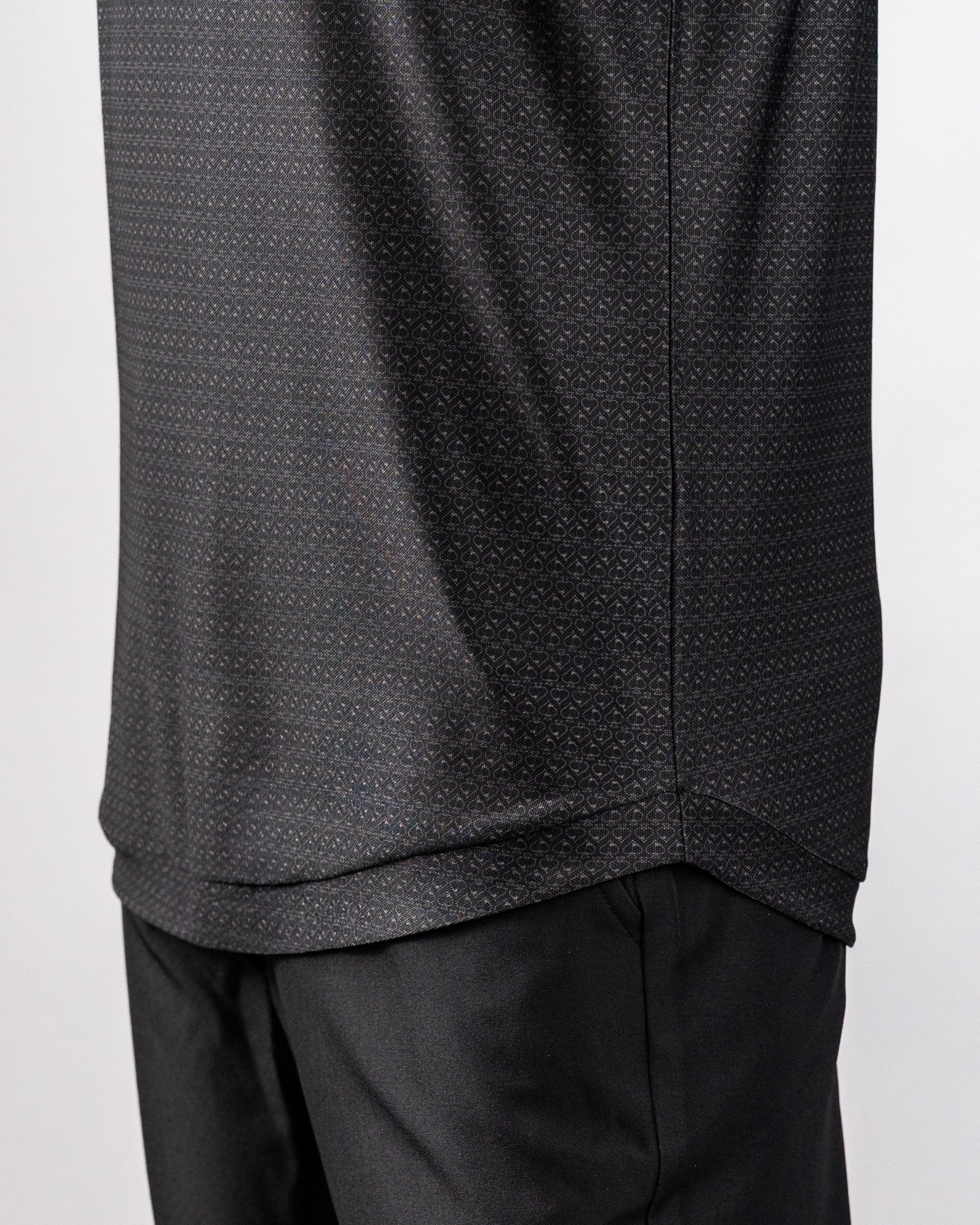 Close-up of a black polo shirt with a subtle, intricate pattern, paired with black pants, showcasing a stylish, modern look.