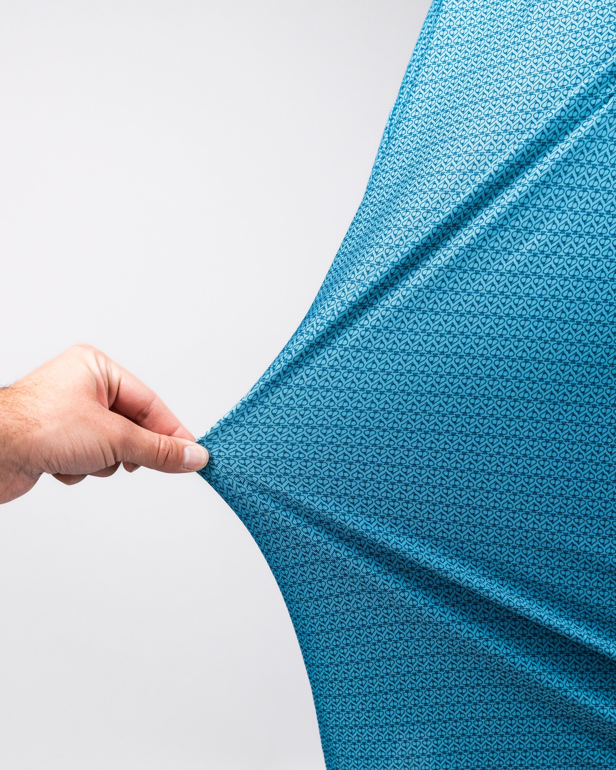 Close-up of a hand stretching a blue Player Preferred™ Polo in Ocean Spade, featuring a small, intricate geometric pattern.