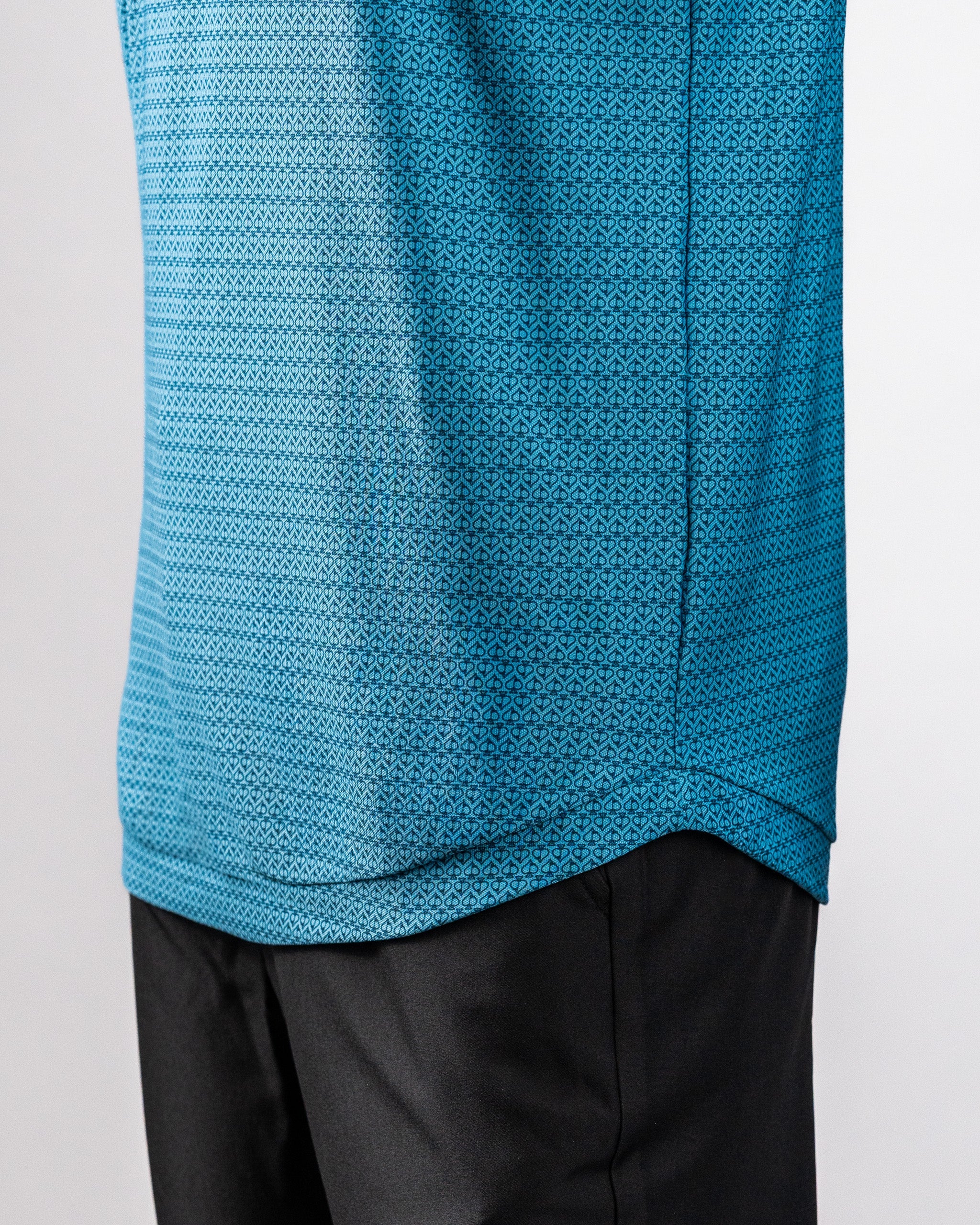 Close-up of a blue Player Preferred™ Polo shirt with a geometric pattern, worn over black pants.
