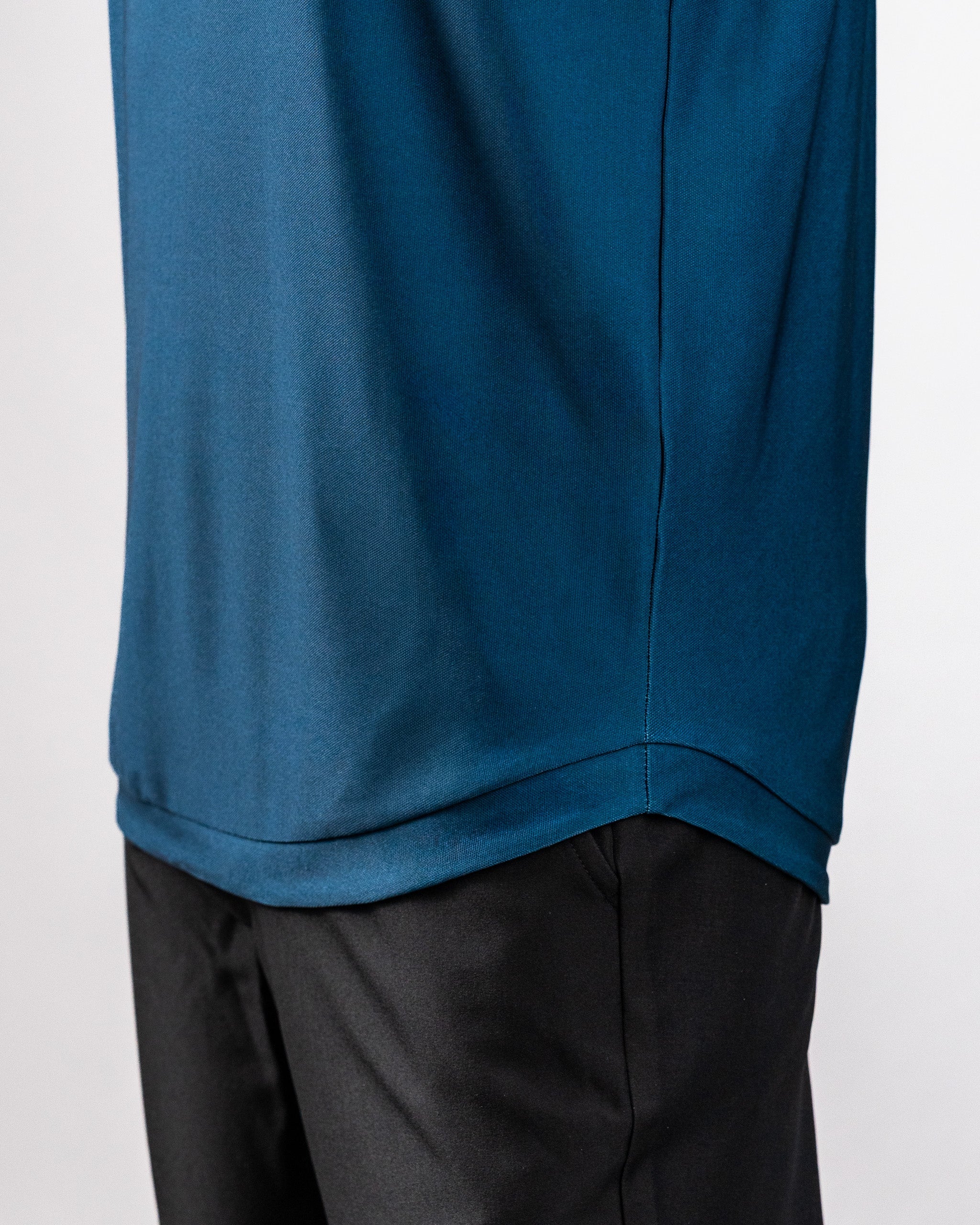 Close-up of a navy Player Preferred™ Polo with Spade Fade design, worn over black pants, showing fabric texture and stitching.