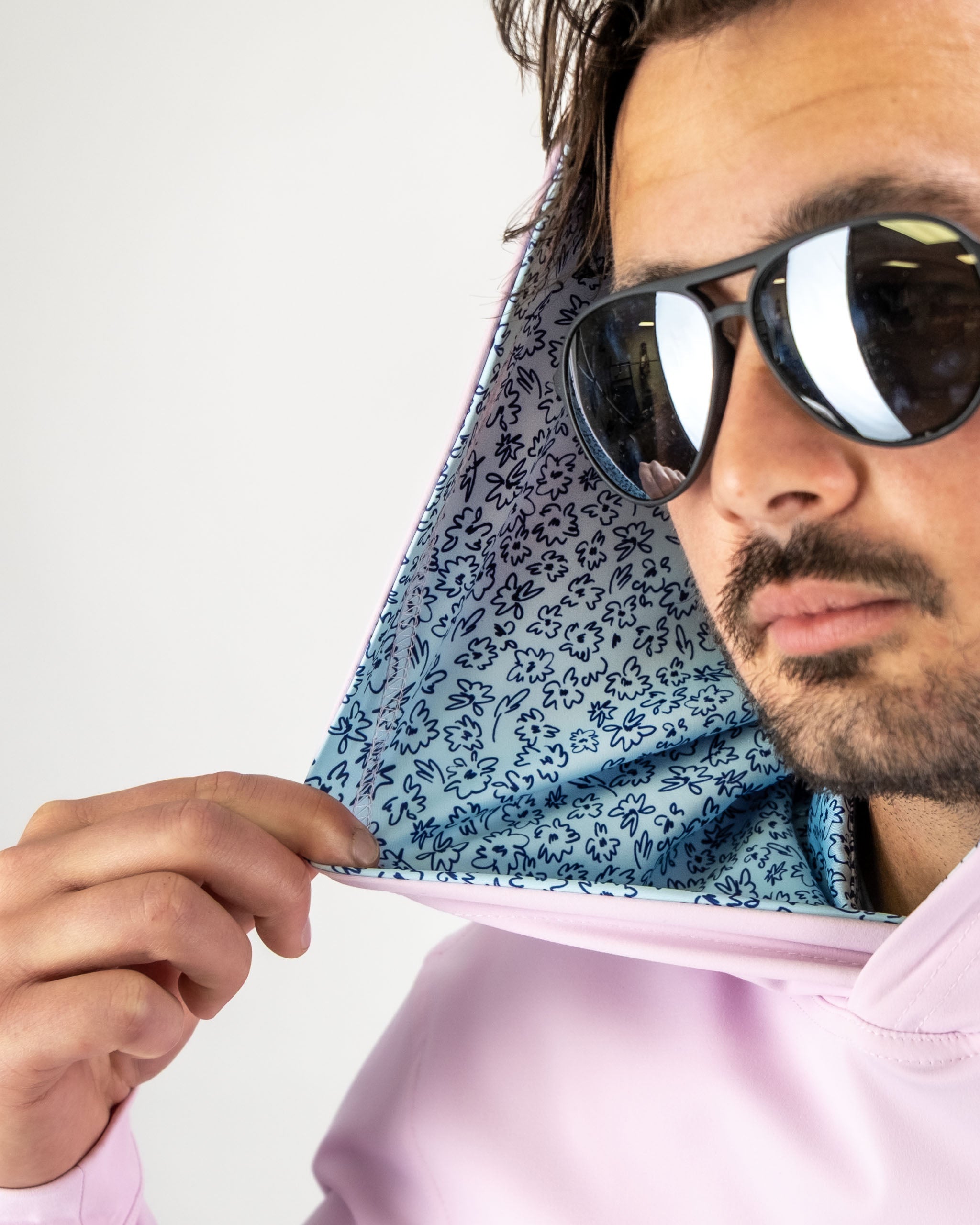 Man wearing a pink performance golf hoodie with a blue floral pattern lining in the hood, showcasing a stylish look.