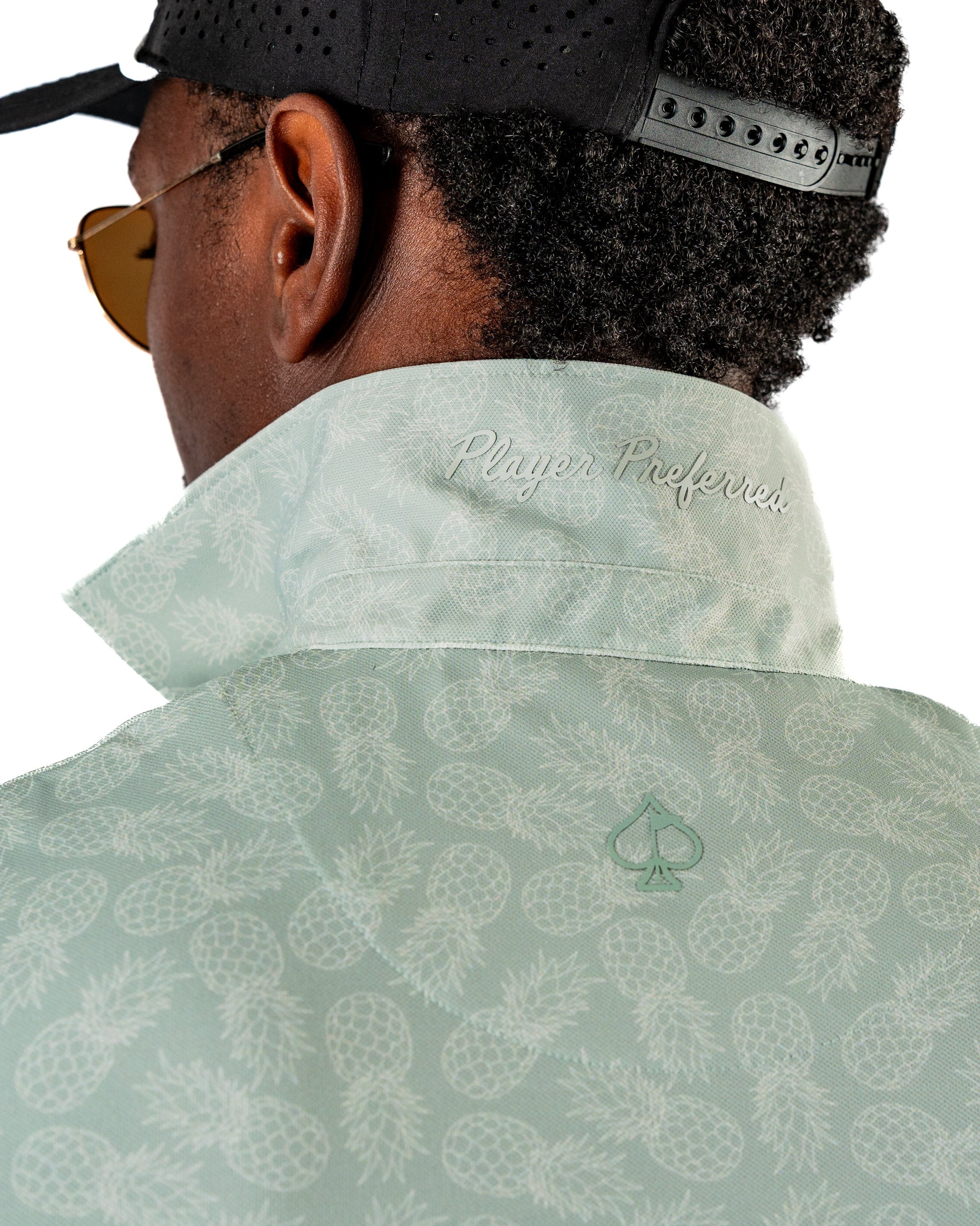 Man wearing a mint green jacket with a pineapple pattern and the text "Player Preferred" embroidered on the collar.