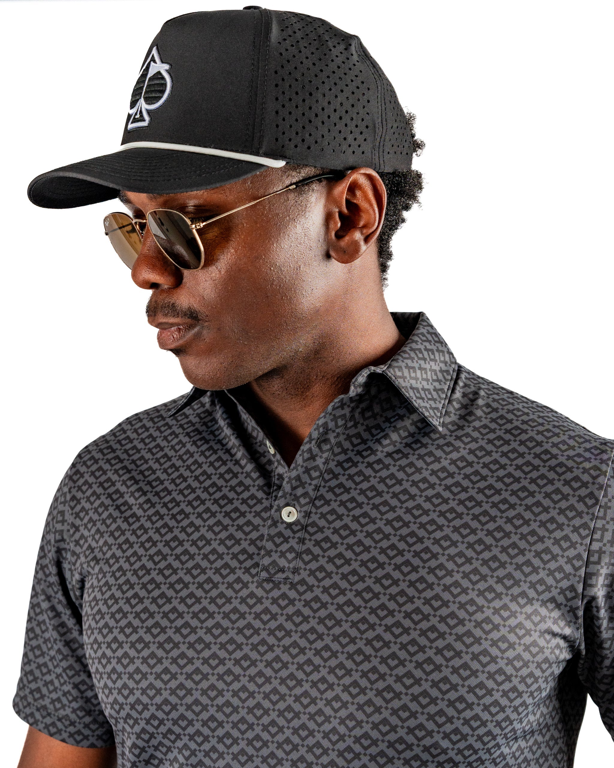 Man wearing a stylish slate mosaic golf polo shirt and a black cap, showcasing a modern and bold golf look.