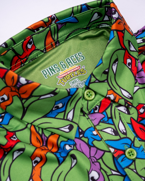 Colorful youth shirt featuring a vibrant Teenage Mutant Ninja Turtles design with playful expressions on a green background.