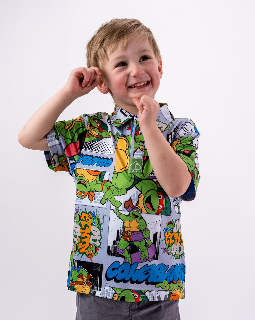 Youth wearing a colorful TMNT comic strip shirt, smiling and posing playfully against a white background.