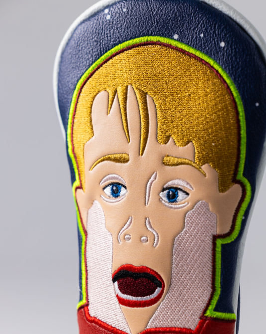 Bold golf headcover featuring a vibrant, embroidered design of a surprised face with a wide-open mouth and expressive features.