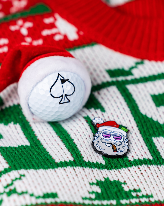 Santa the Degenerate Ball Marker featuring a playful Santa design, placed on a festive holiday sweater with a golf ball.
