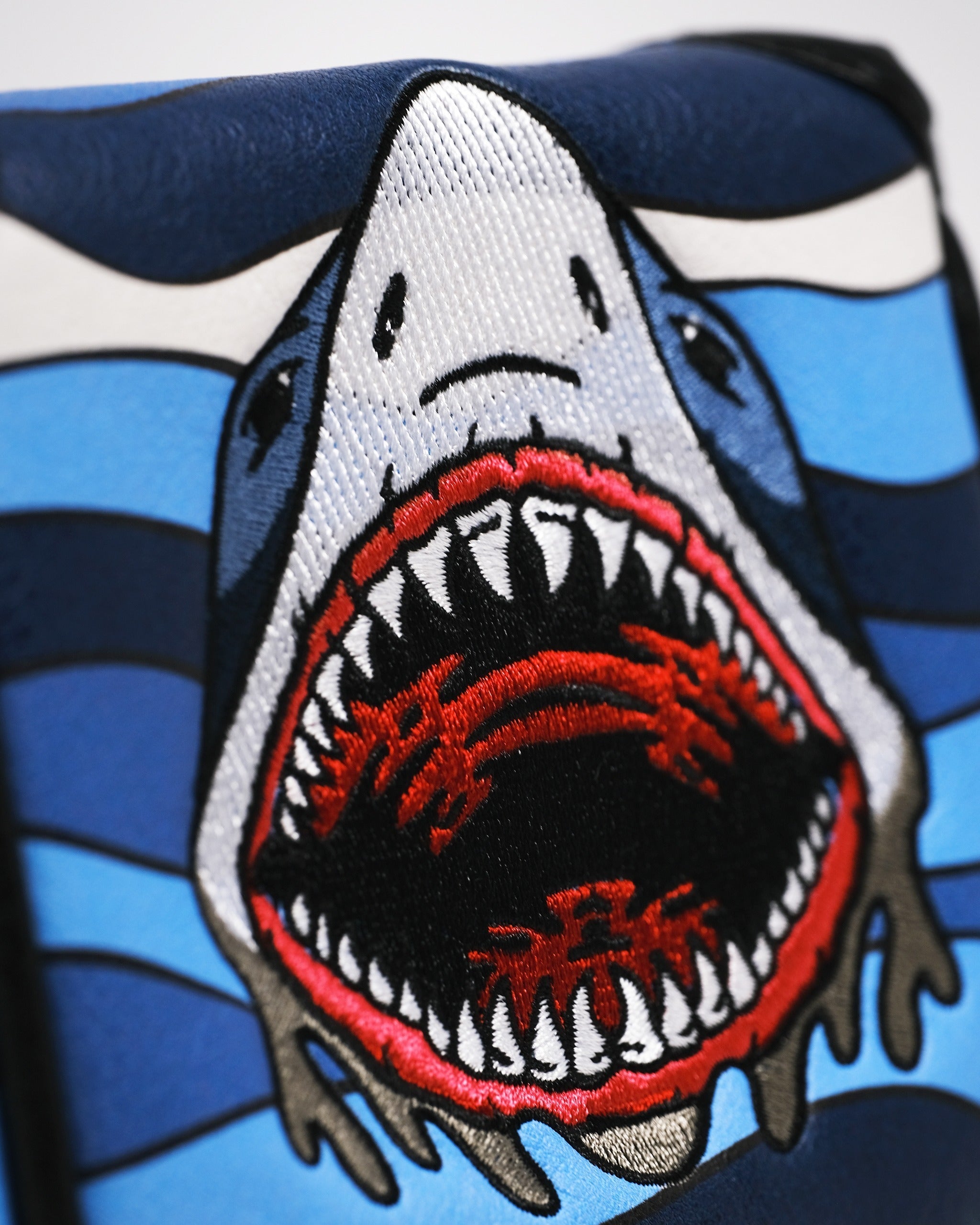 Bold mallet putter cover featuring a fierce shark design with vibrant blue stripes, perfect for standout golfers.