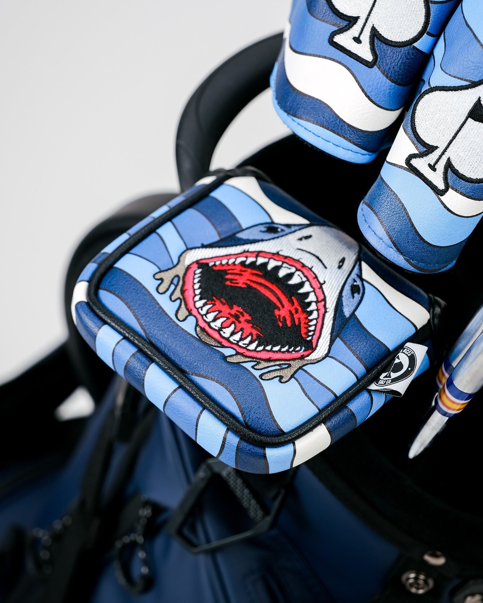Bold shark-themed mallet cover featuring vibrant blue stripes and a fierce open-mouth design, perfect for standout golfers.